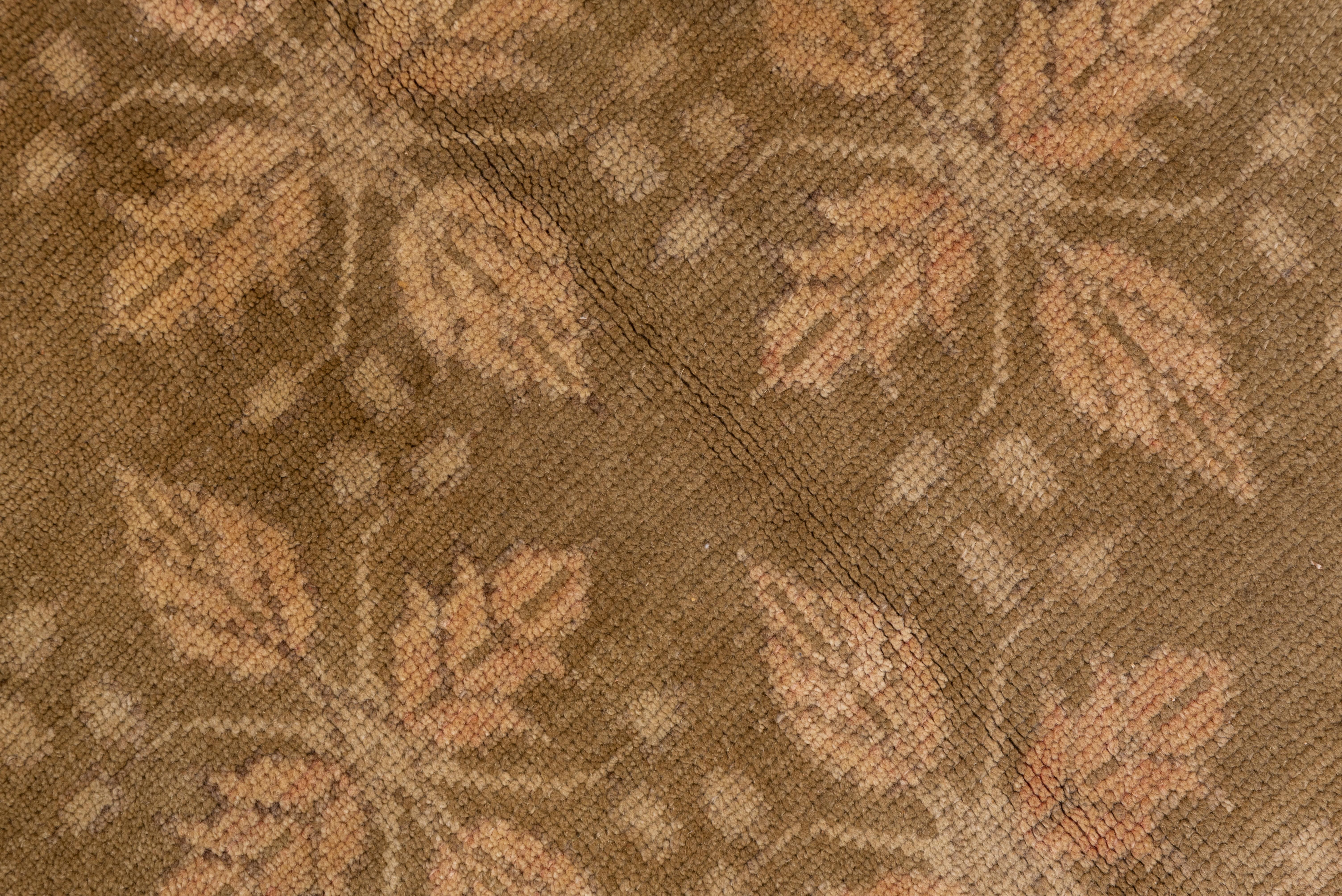 An all-over pattern of half-drop straw quatrefoil leaf motives with berry finials covers the grassy olive green ground of this vintage Turkish small carpet, framed by a brownish-grey border with an attenuated flowering Meander, rosettes, and