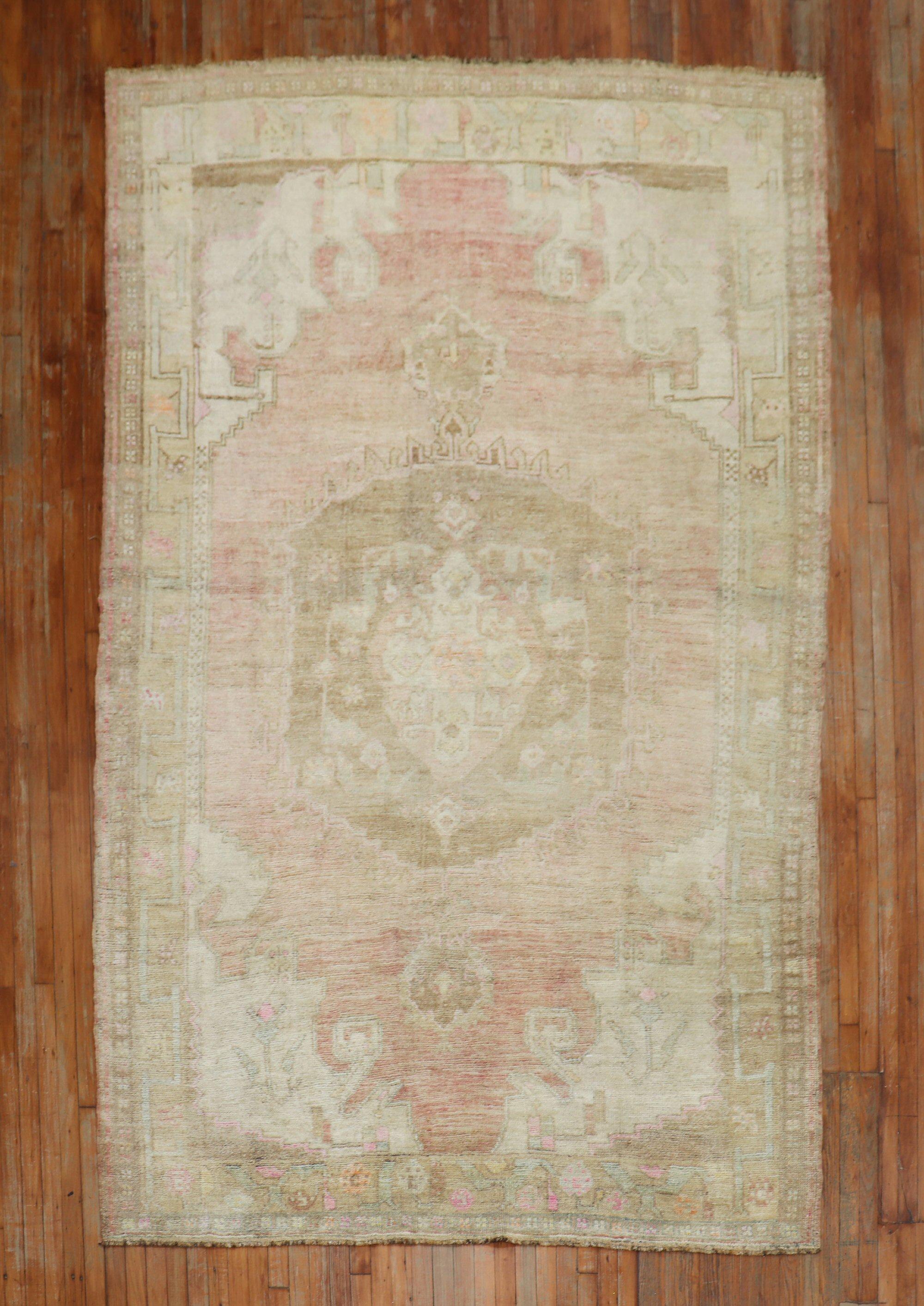 A vintage Turkish rug with a central medallion on a pink field. accents in white and brown

Measures: 6'8'' x 10'8''.