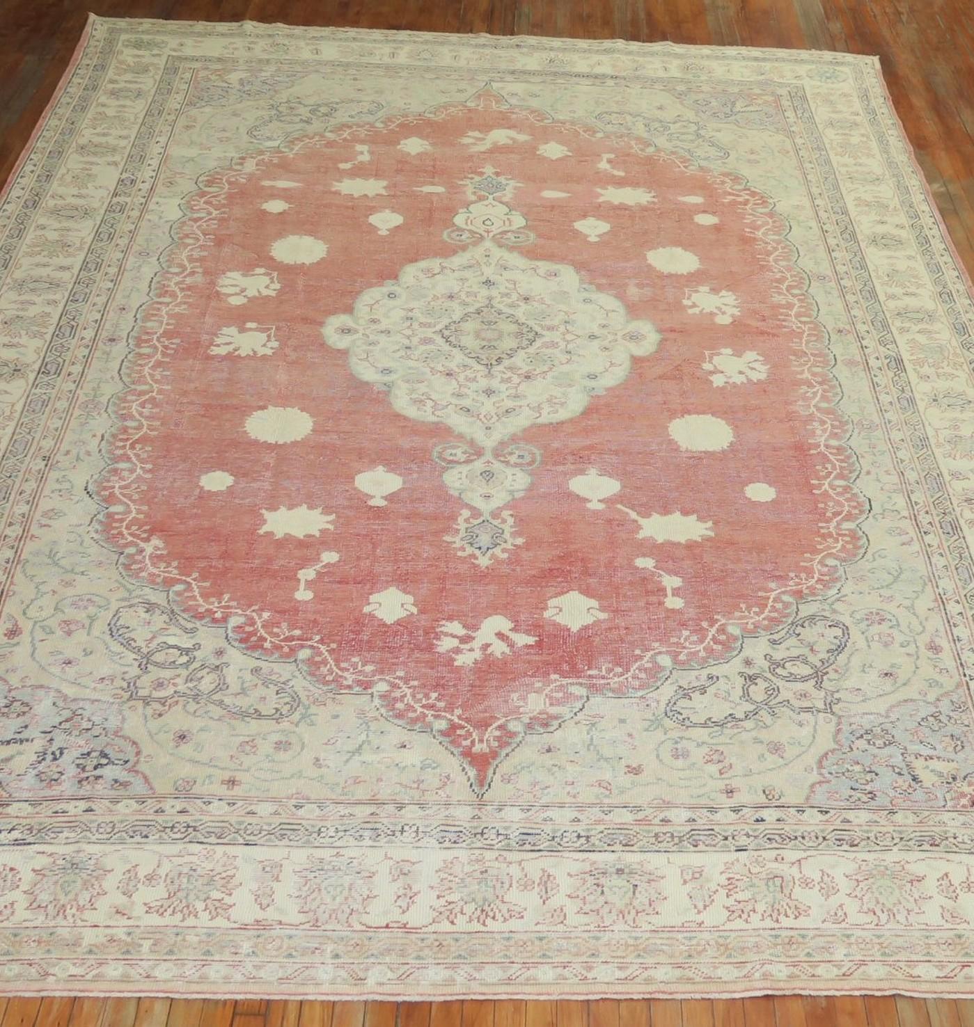 An oversize old Turkish Oushak rug, with ivory, soft brown, and light green accents and predominantly soft red tone, circa 1930.

Size: 10'5