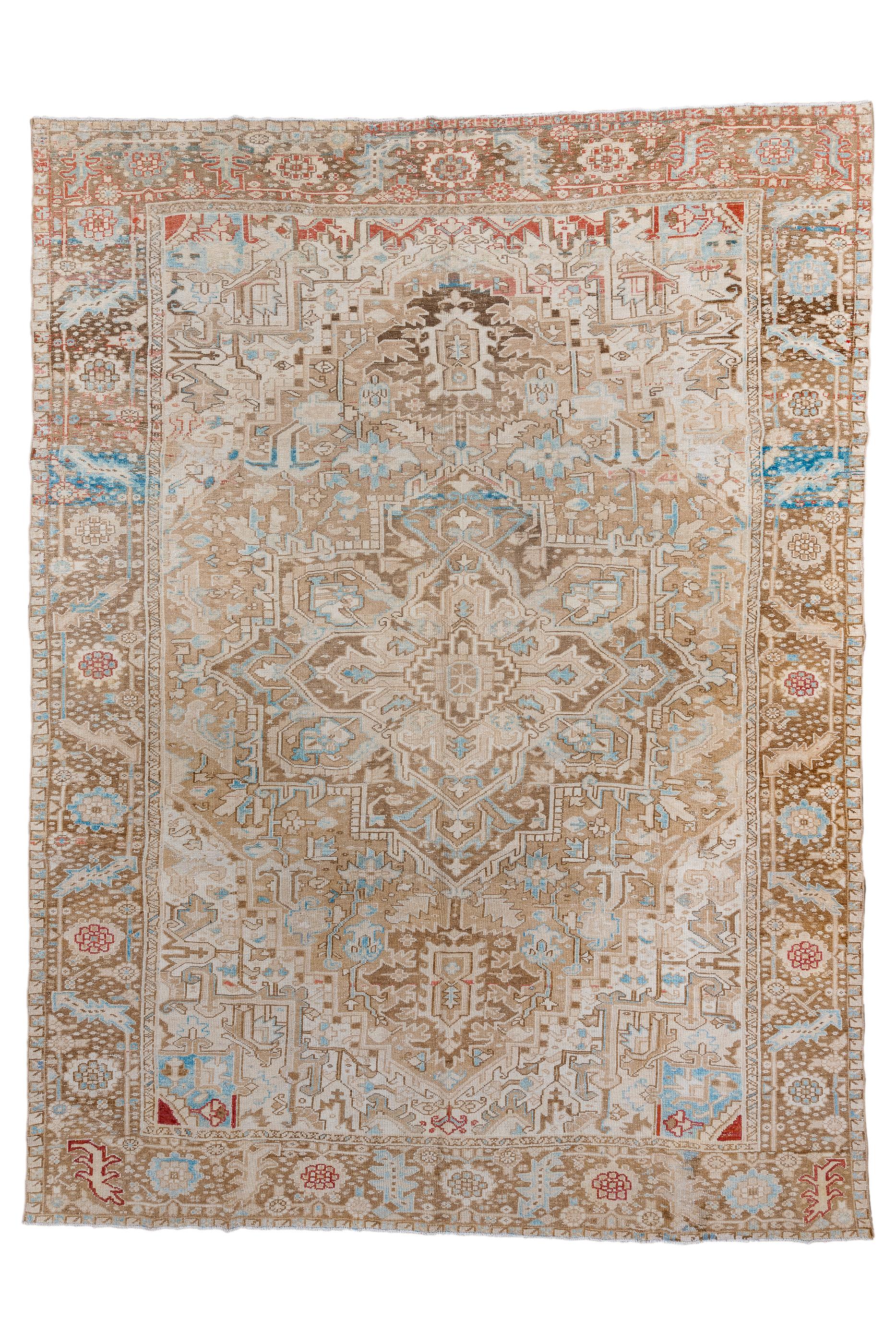 This is a softer-toned Heriz with a light coral field centred by a dark slate octogramme medallion enclosing for projecting palmettes, and with large torn palmette pendants in darker blue.  Semi-geometric flowers in field and ecru-sand corners. 