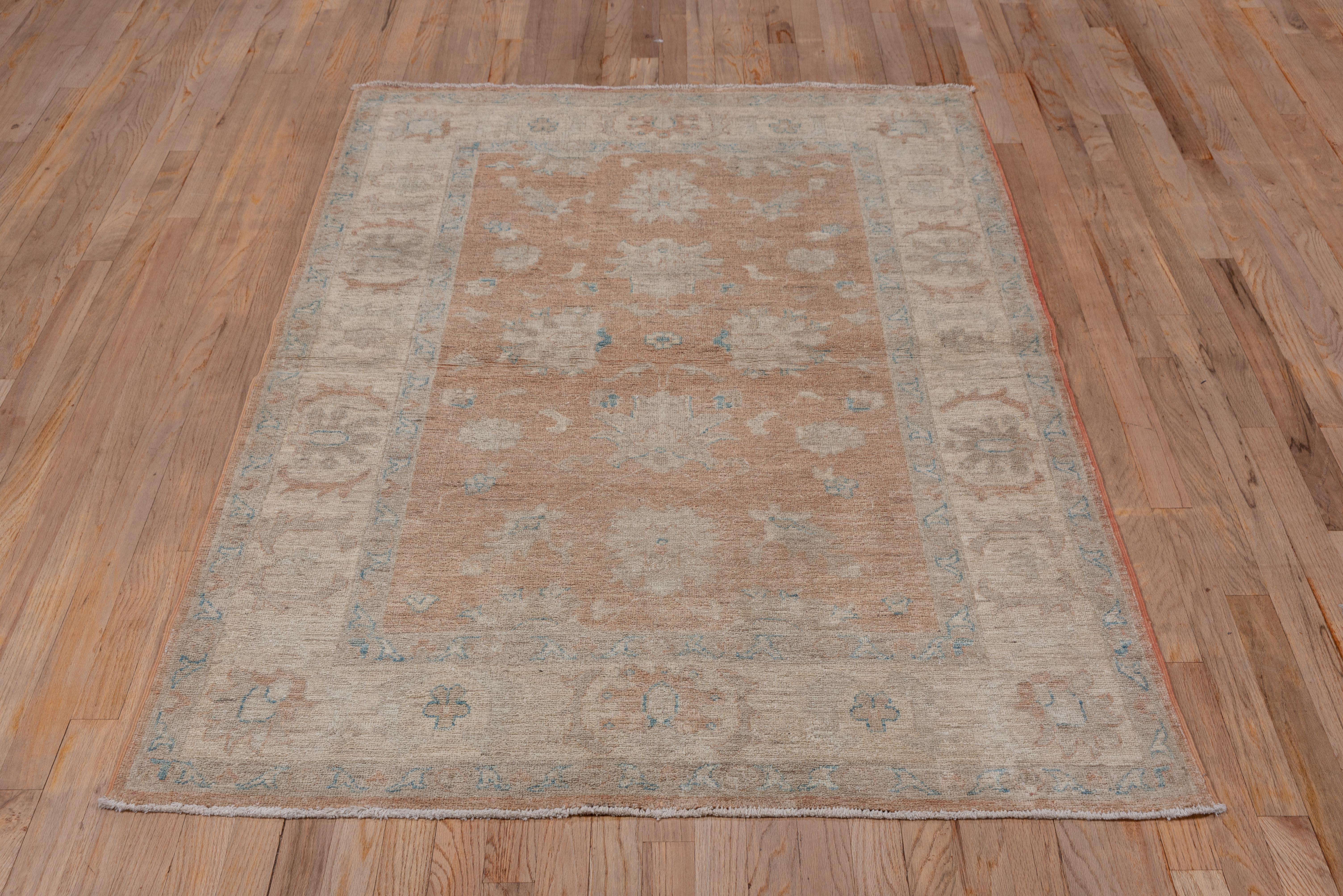 In the general Oushak style, this softly toned scatter rug shows well-spaced ragged and finger palmettes on the abrashed light brown or tan ground. The sand border presents more finger palmettes and bracketing saz leaves.
