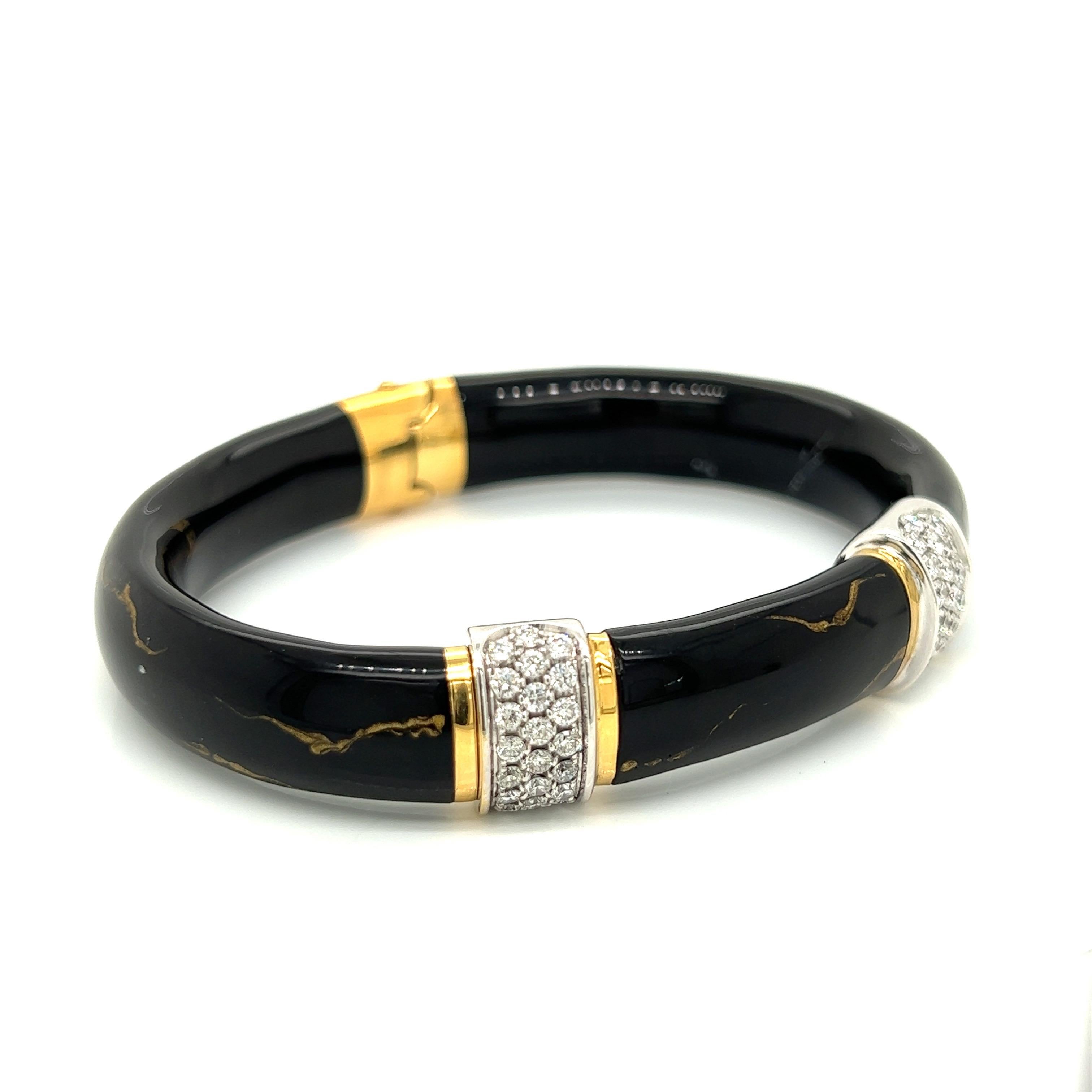 Soho's black and gold bangle is handcrafted in Italy. The traditional yet modern bangle is 18kt. white and yellow gold, enamel, and 1.32 ctw in diamonds. The 11mm wide bangle has a hidden hinge on top. Interior dimensions are 2.5