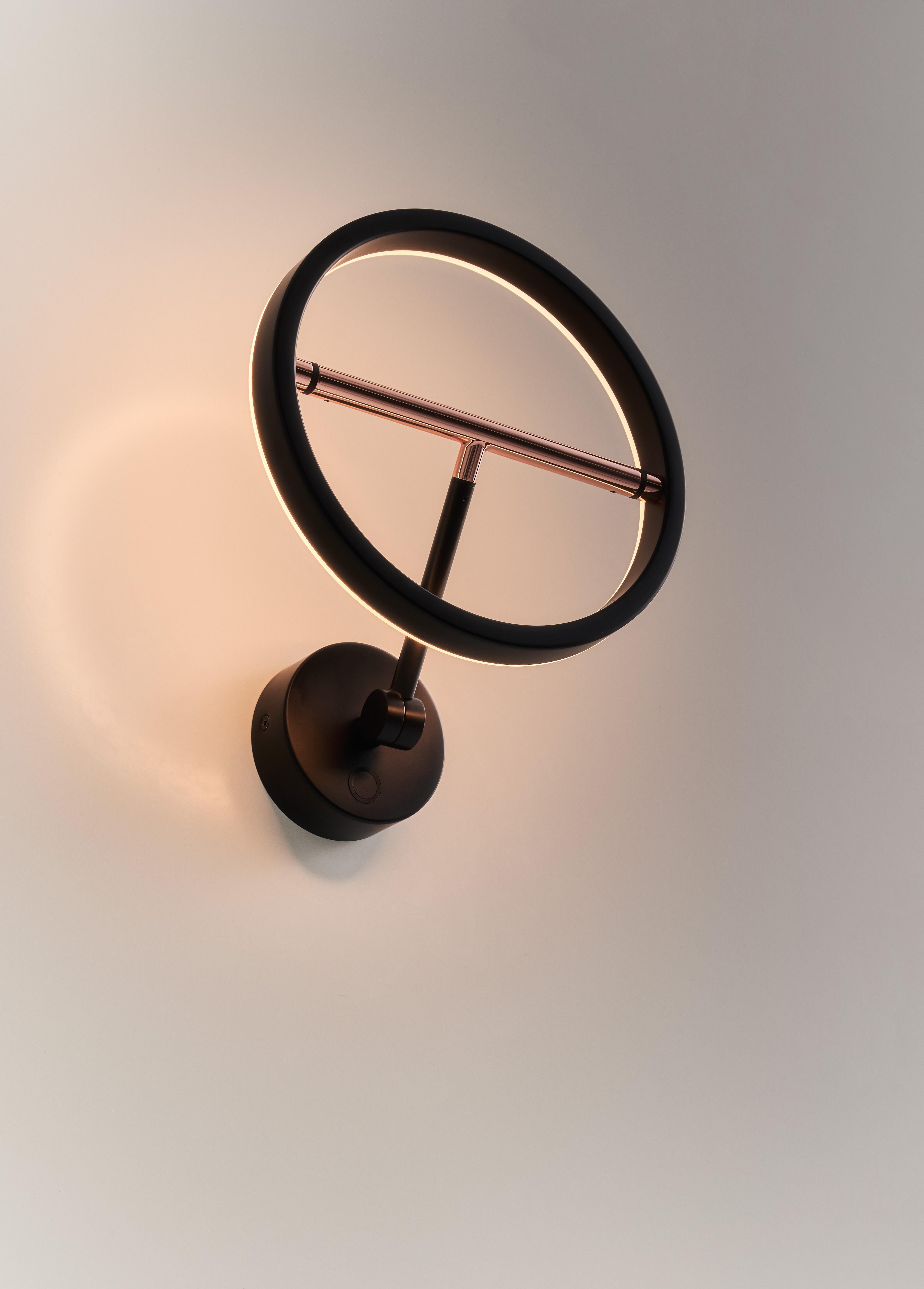 Die Collection'S ist ein zurückhaltendes Design mit durchdachten Überlegungen und besteht aus Hänge-, Tisch- und sogar Stehlampen. Der ringförmige Lampenschirm der SOL Wall Sconce ist fein auf einem metallisch glänzenden Balancierbalken befestigt