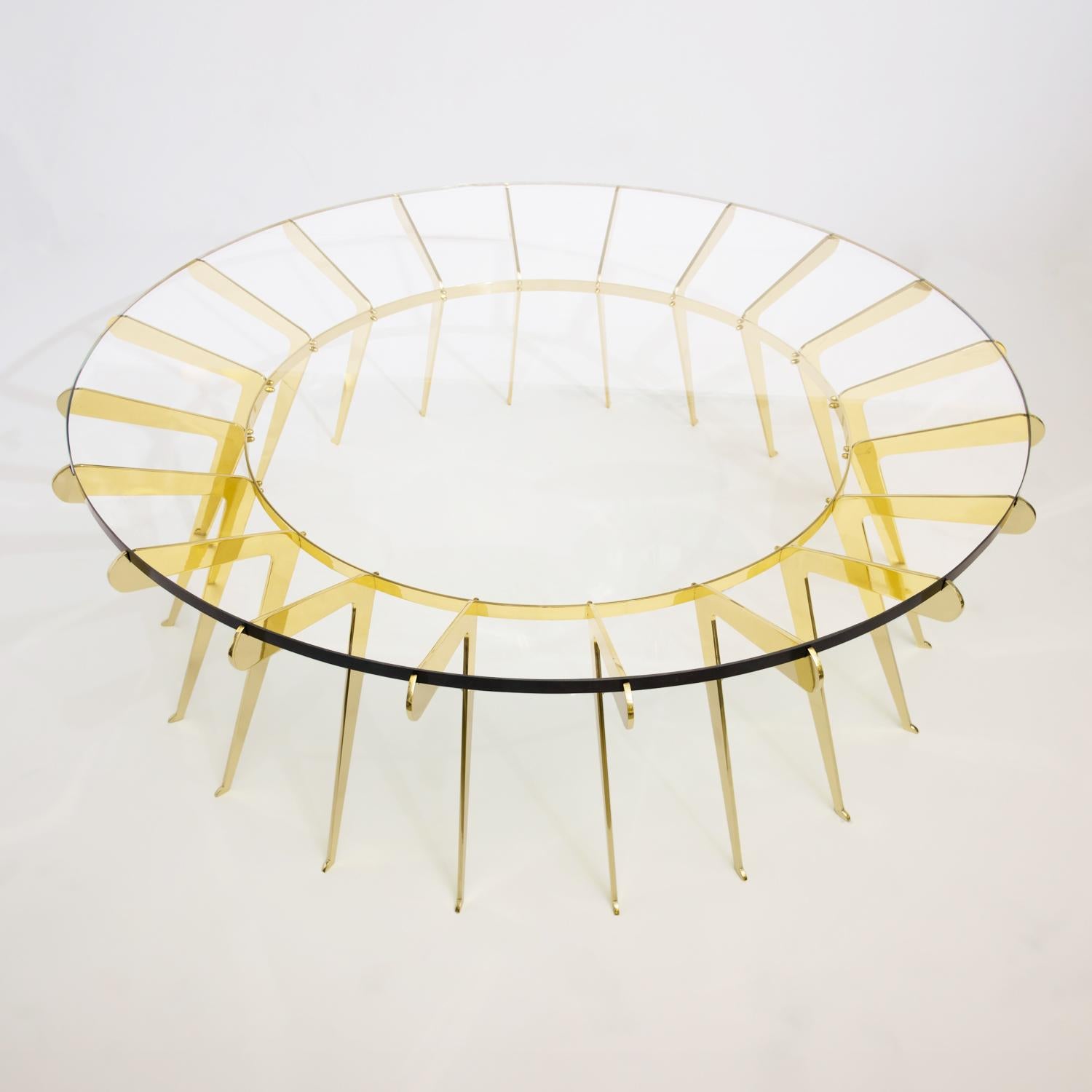 Der Tisch Solare spielt mit dem Konzept der Stärke in Zahlen, bei dem zahlreiche zart gestaltete Messingbeine zusammenkommen, um eine dicke Klarglasplatte zu halten. Abgebildet in poliertem Messing mit einem Durchmesser von 51