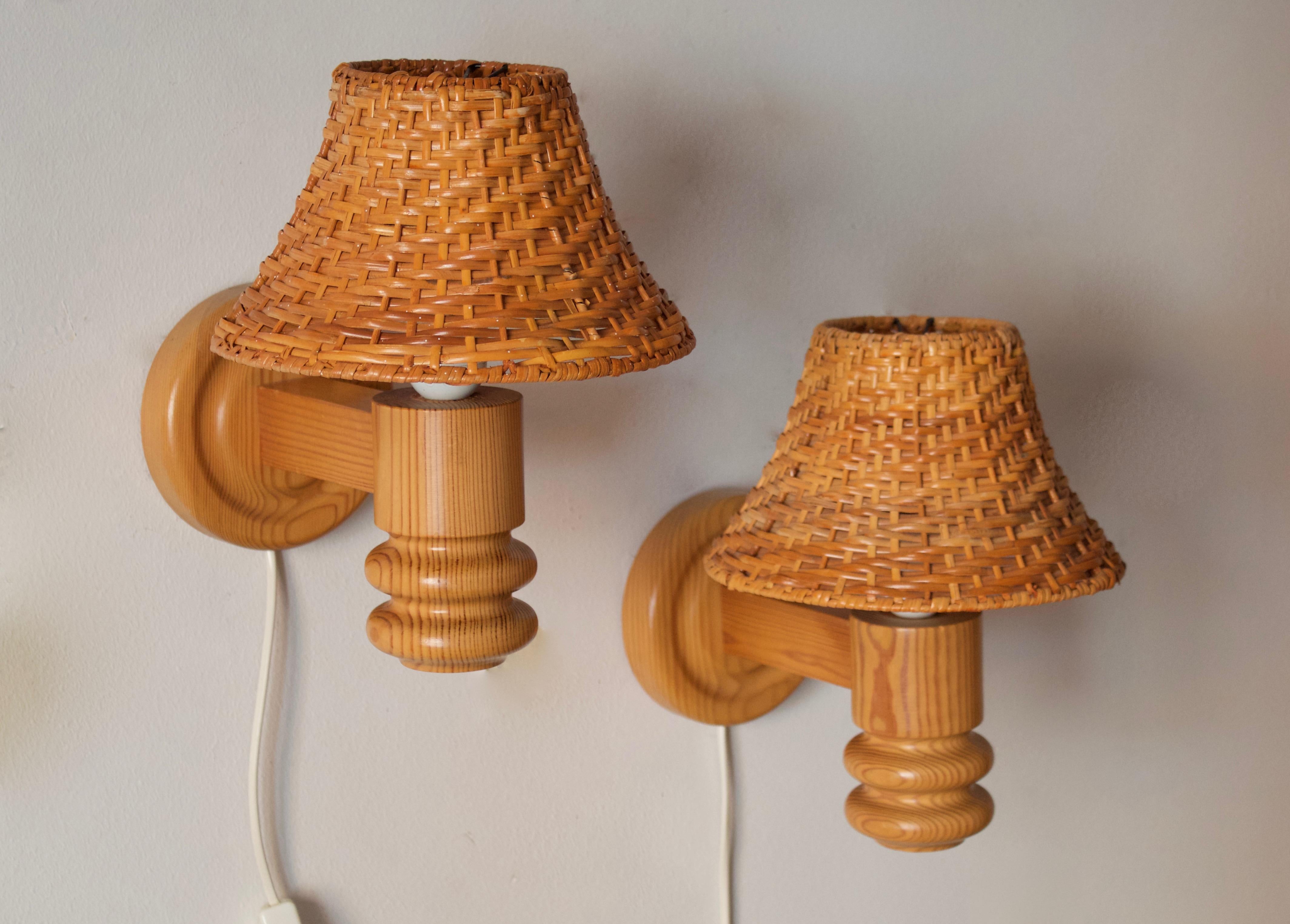 A pair of wall lights / sconces. Produced by Solbackens Svarveri. Sweden, circa 1970s. Assorted vintage rattan lampshades.

Stated dimensions include rattan lampshades as illustrated. Lampshades included in purchase might vary very slightly to