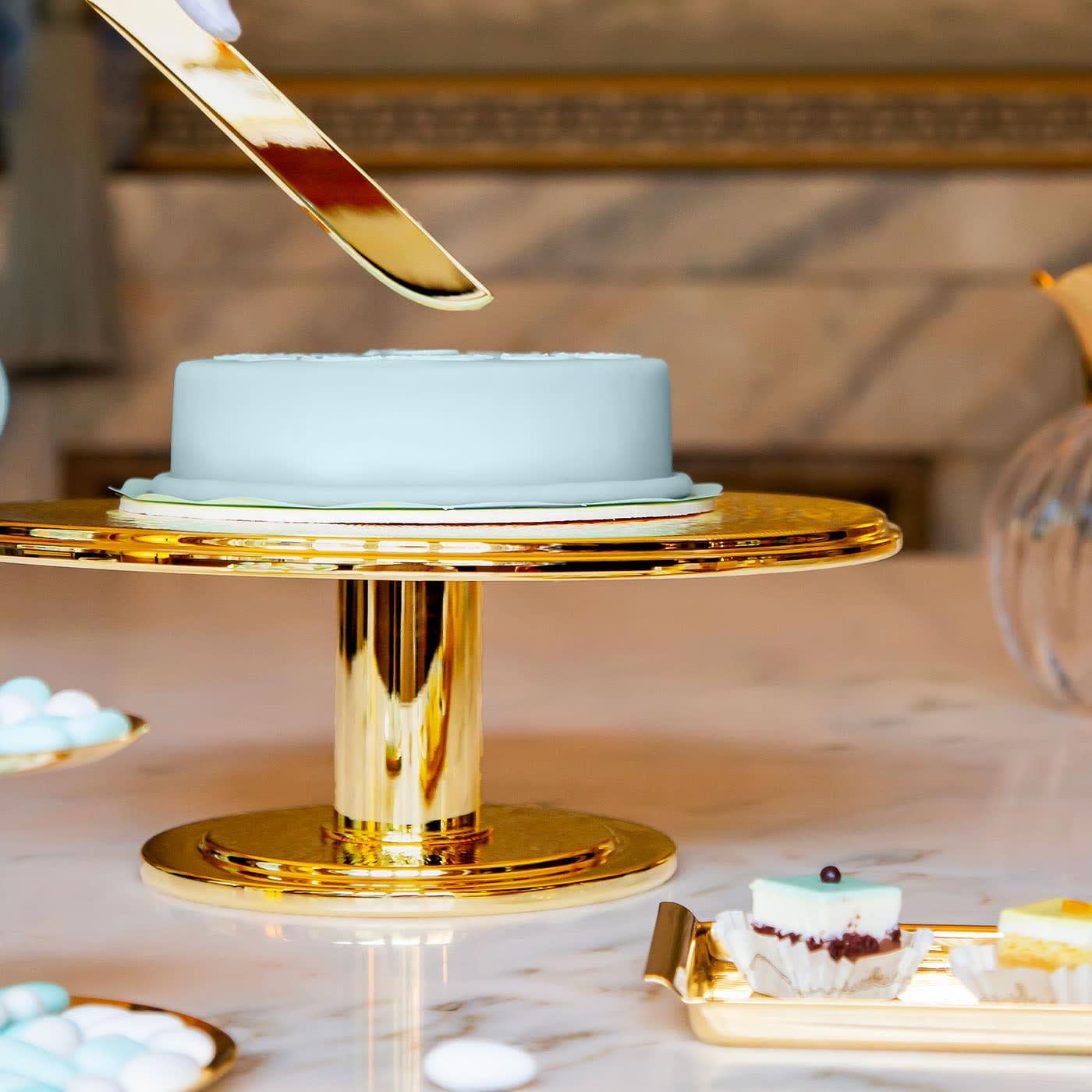Playfully named after the sun due to its gleaming look and texture of tiny radially-juxtaposed traits reminiscent of sunbeams, this cake stand is a plush design luxuriously plated in gold. A soft stepped design marks both the top and the base, a