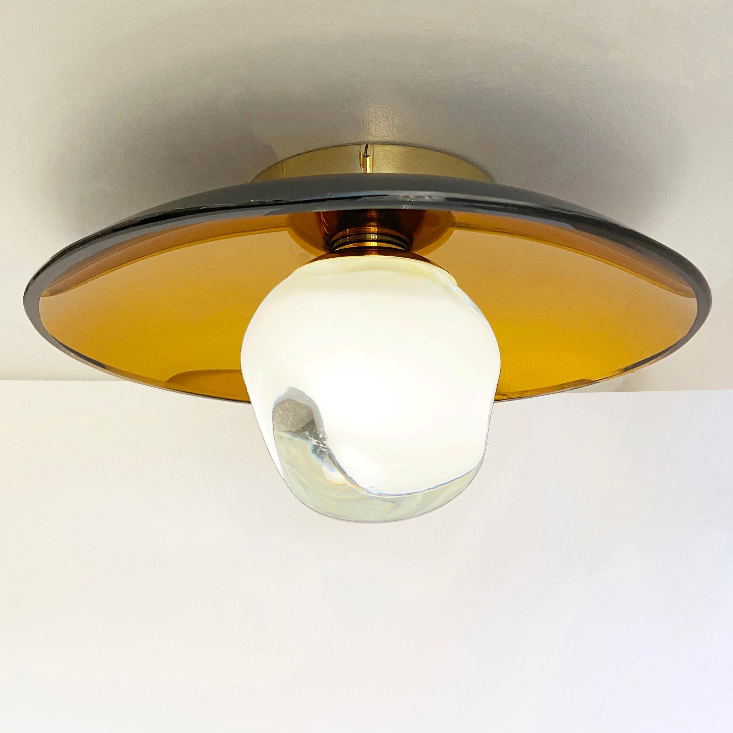 The versatile Sole light can be installed as a ceiling light or wall light and features our handblown Sfera glass mounted on a colored reflective glass dish. Shown with the amber colored reflective glass and polished brass hardware.

Customization