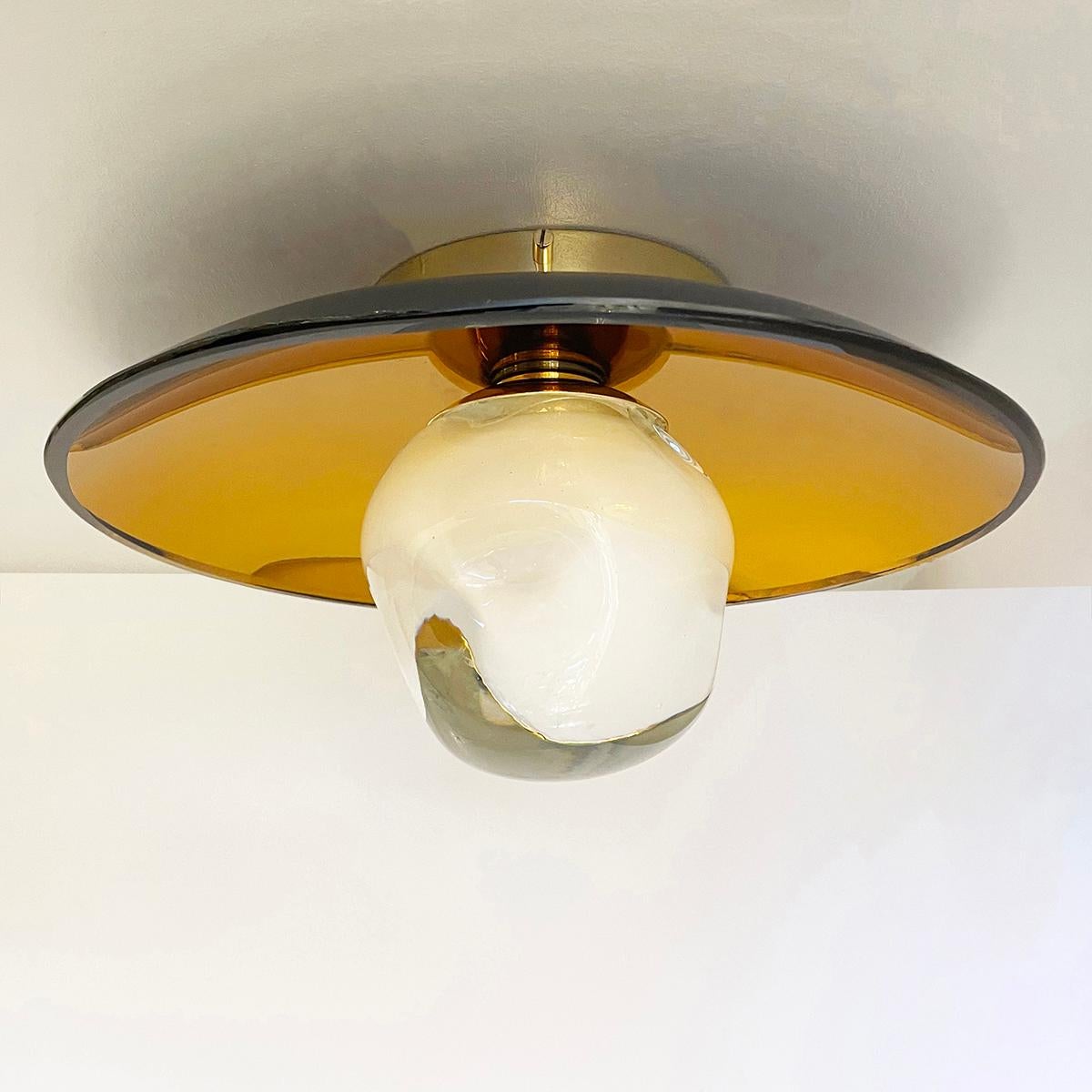 The versatile Sole light can be installed as a ceiling light or wall light and features our handblown Sfera glass mounted on a colored reflective glass dish. Shown with the amber colored reflective glass and polished brass hardware.

The concave