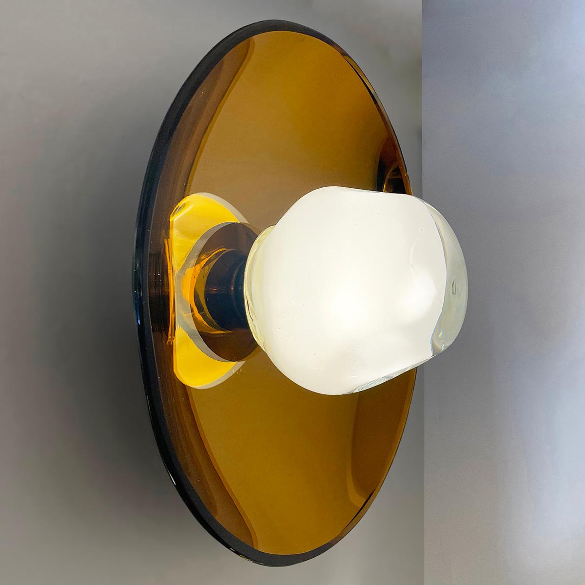 The versatile Sole light can be installed as a ceiling light or wall light and features our handblown Sfera glass mounted on a colored reflective glass dish. Shown with the amber colored reflective glass and polished brass hardware.

The concave