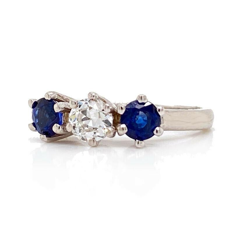 Excellent condition. This solid 14K white gold three stone ring features two round genuine blue sapphires that measures 3.92mm approximately. In between the sapphires is a natural old European cut diamond that weighs approximately 0.30ct and is