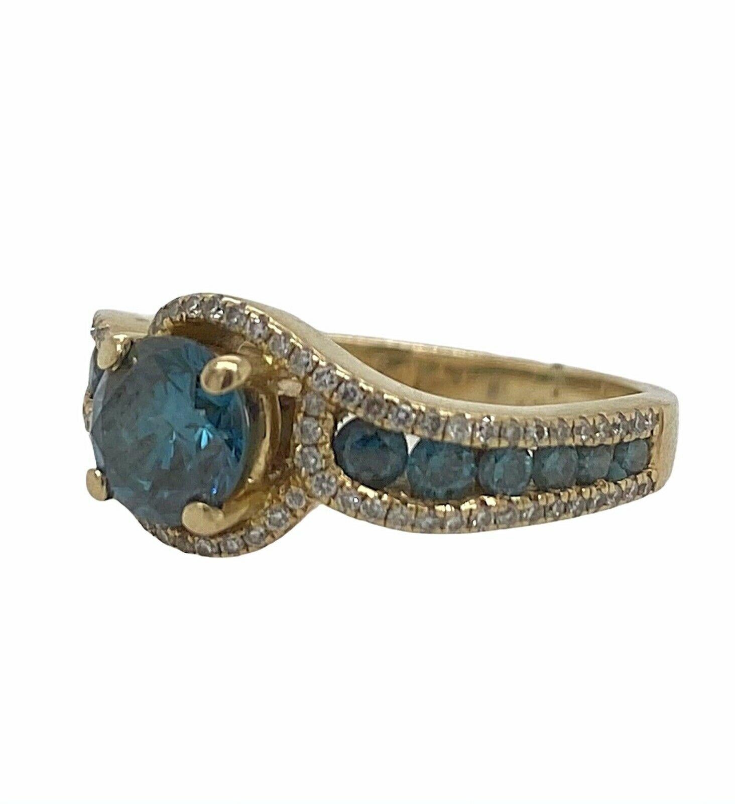 Excellent condition. This solid 14K yellow gold ring features a round blue diamond in the center weighing approximately 0.70ct and SI clarity. There are an additional 12 accent blue diamonds that taper on each side and weigh approximately 0.25cttw.