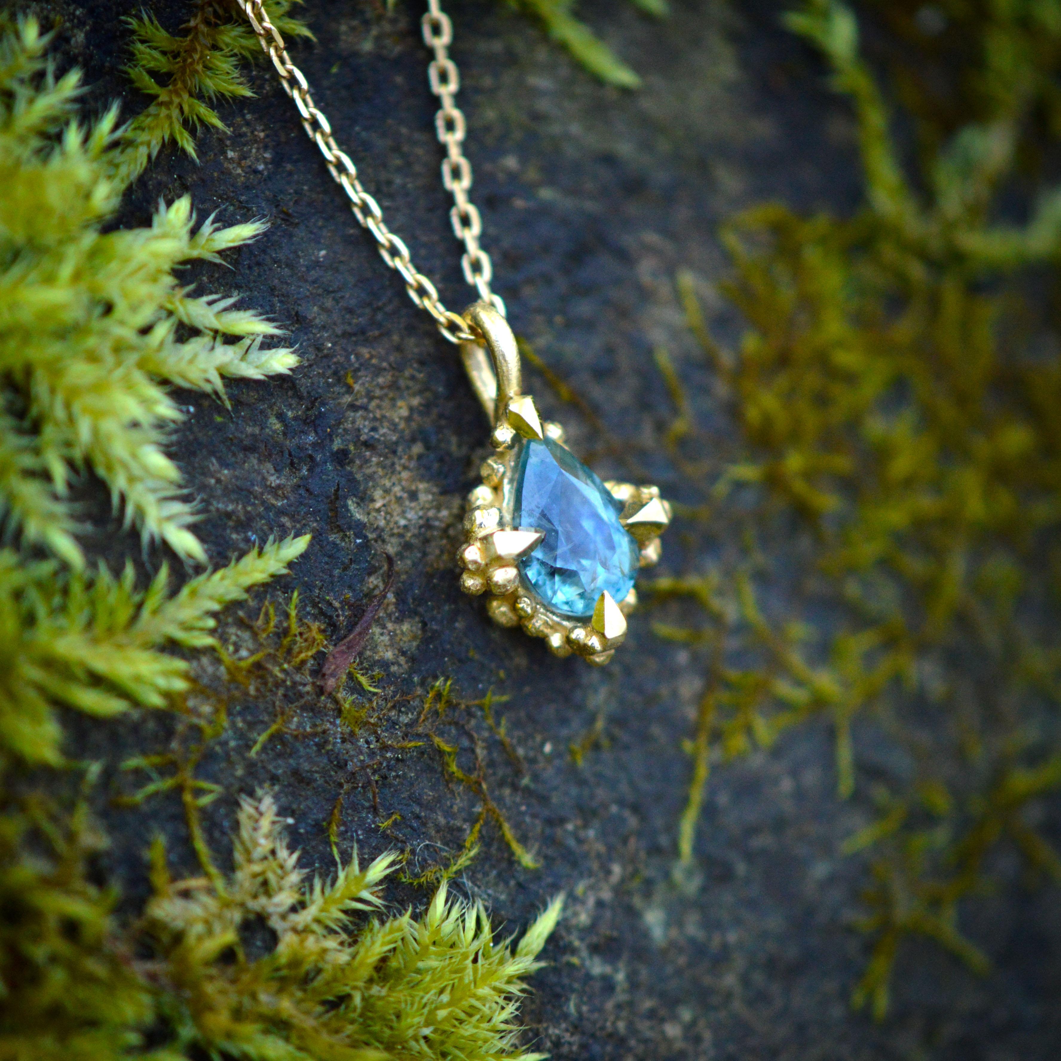 This gnarly ocean inspired pendant is cast in solid 18 carat gold, finished by hand, and set with a teardrop shaped teal sapphire. It is cast in solid 18 Carat gold and finished by hand, and is created from Lucy's original hand-sculpted design.