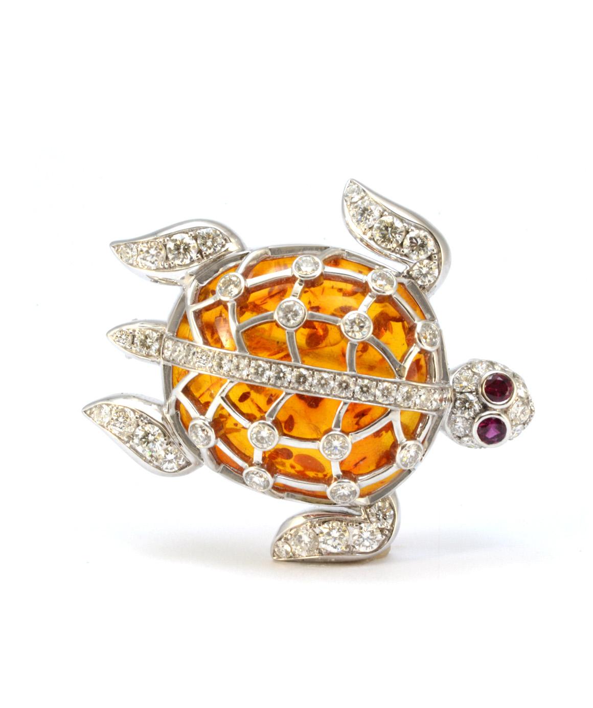 This solid 18k white gold amber, diamond and ruby turtle brooch/pendant is in excellent condition! Measuring approximately 1.5 inches X 1.3 inches, this turtle brooch can be worn as a pin or a pendant. It features 2 ruby eyes measuring approximately