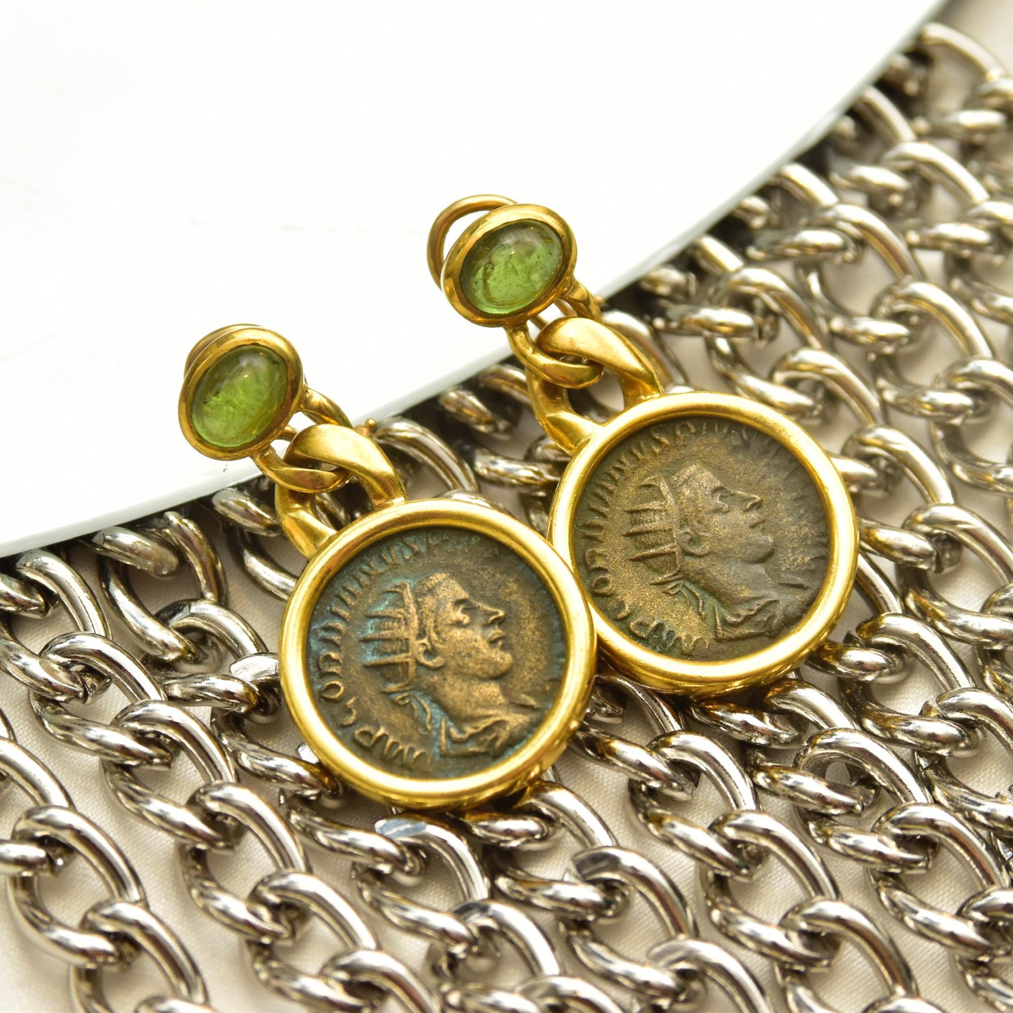 A lavish pair of 18k ancient greek coin dangle earrings with green aventurine accents. Each earring features an open circle bezel set coin, connected via a solid gold chain link to a small gemstone setting. The coins look like they're from the