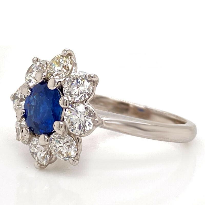 Excellent condition. This solid 18K white gold T. Foster & Co ring features a round genuine blue sapphire that measures 6.25mm and is surrounded by 8 high quality natural round brilliant diamonds that weigh approximately 1.60CTTW and are E-F/VVS.