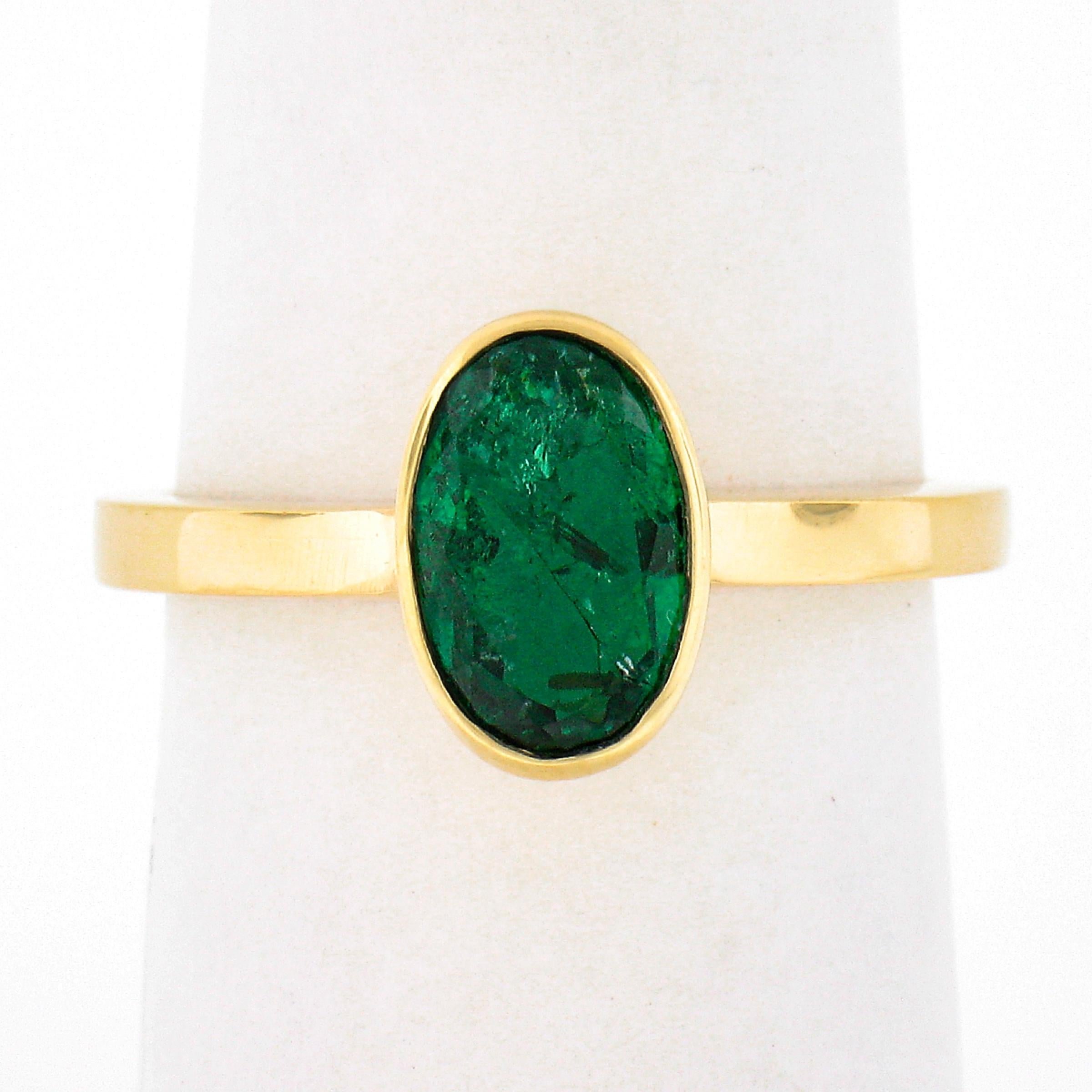 This beautiful emerald solitaire ring is crafted in solid 18k yellow gold and features a genuine emerald neatly bezel set at the center. This oval cut solitaire has a gorgeous, rich, dark green color with very nice shine due to its brilliant cutting