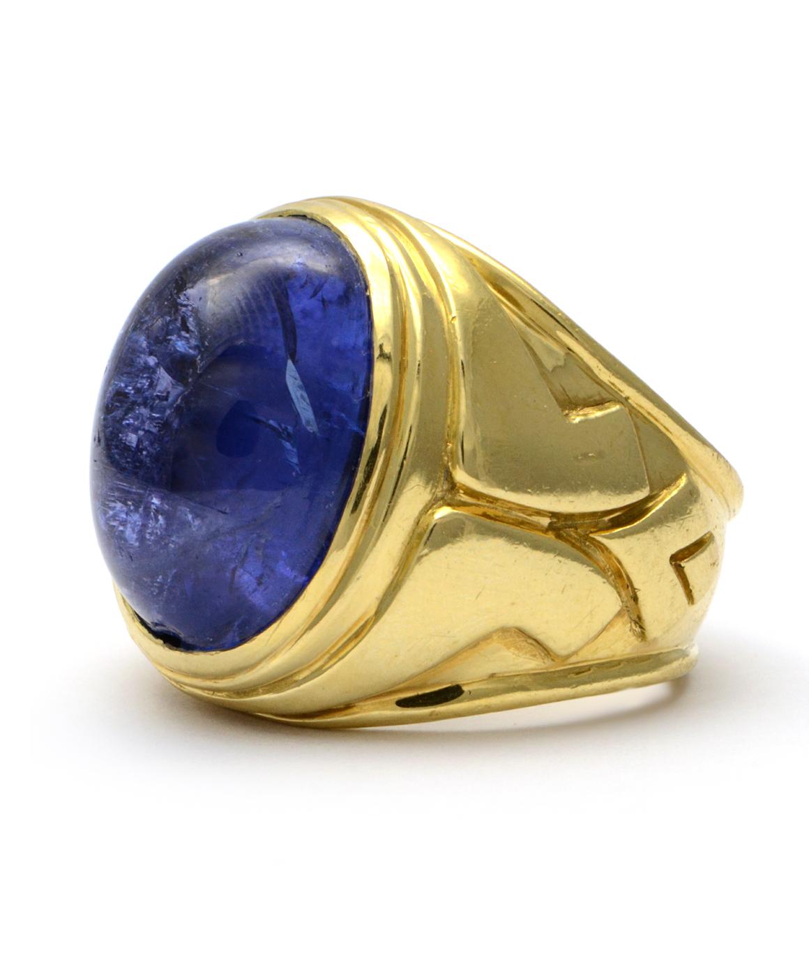 Excellent condition. This men's ring in solid 18K yellow gold features an oval cabochon genuine tanzanite that measures approximately 16.45mm in length X 11.65mm wide. The tanzanite is a gorgeous deep blue/purple color. The ring is a size 6.75 and