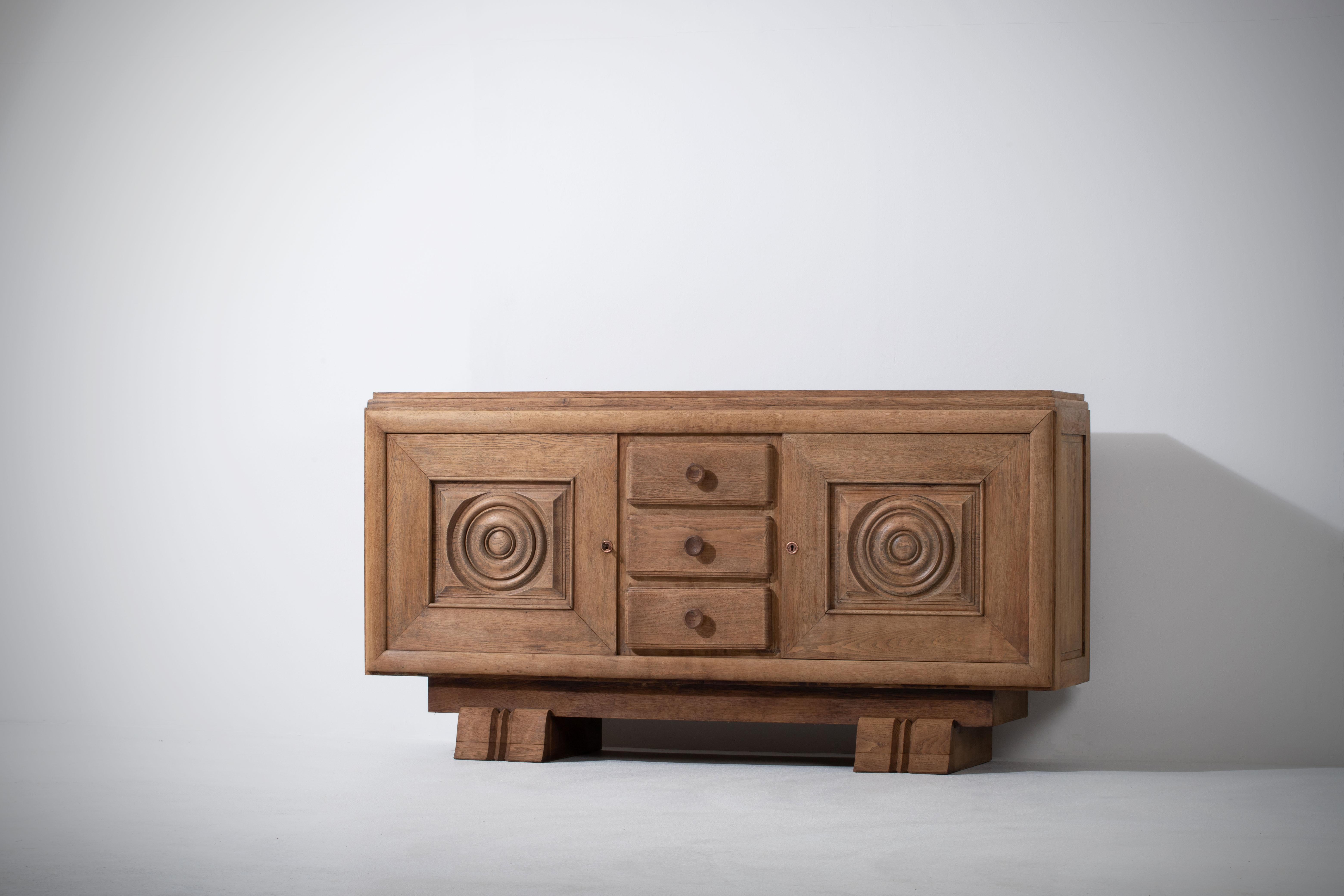 A large sideboard/credenza presumably by Charles Dudouyt. 
France, circa 1930s.
Consists of two doors providing shelves storage compartments and a column of drawers in the center.
Signature circular shaped doors and trestle legs.
The sideboard