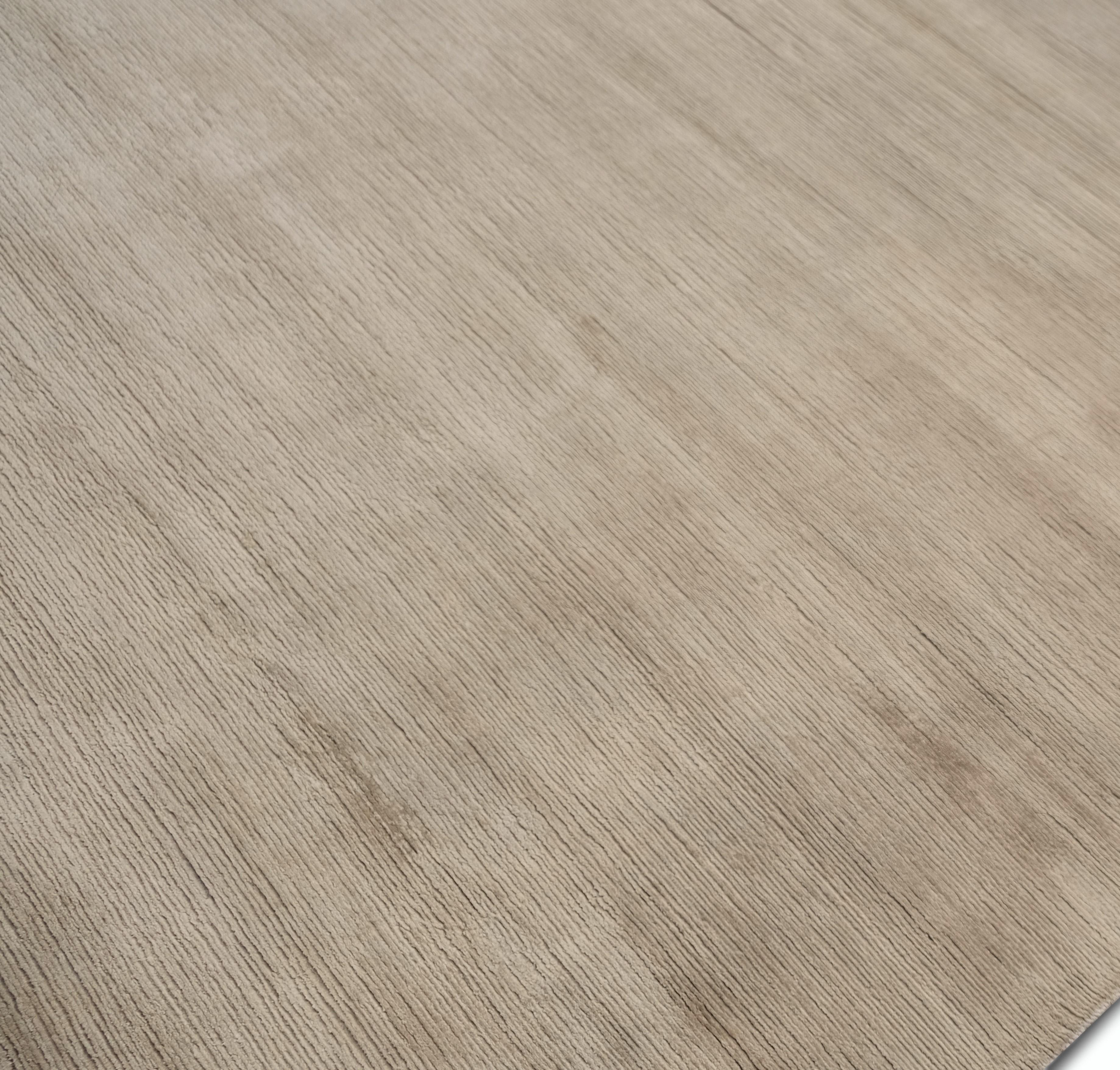 This hand-knotted silk rug embodies understated elegance with its sophisticated minimalist design and luxurious texture. Crafted from premium silk, this rug features a soft, monochromatic palette in neutral beige tones, offering a sheen that