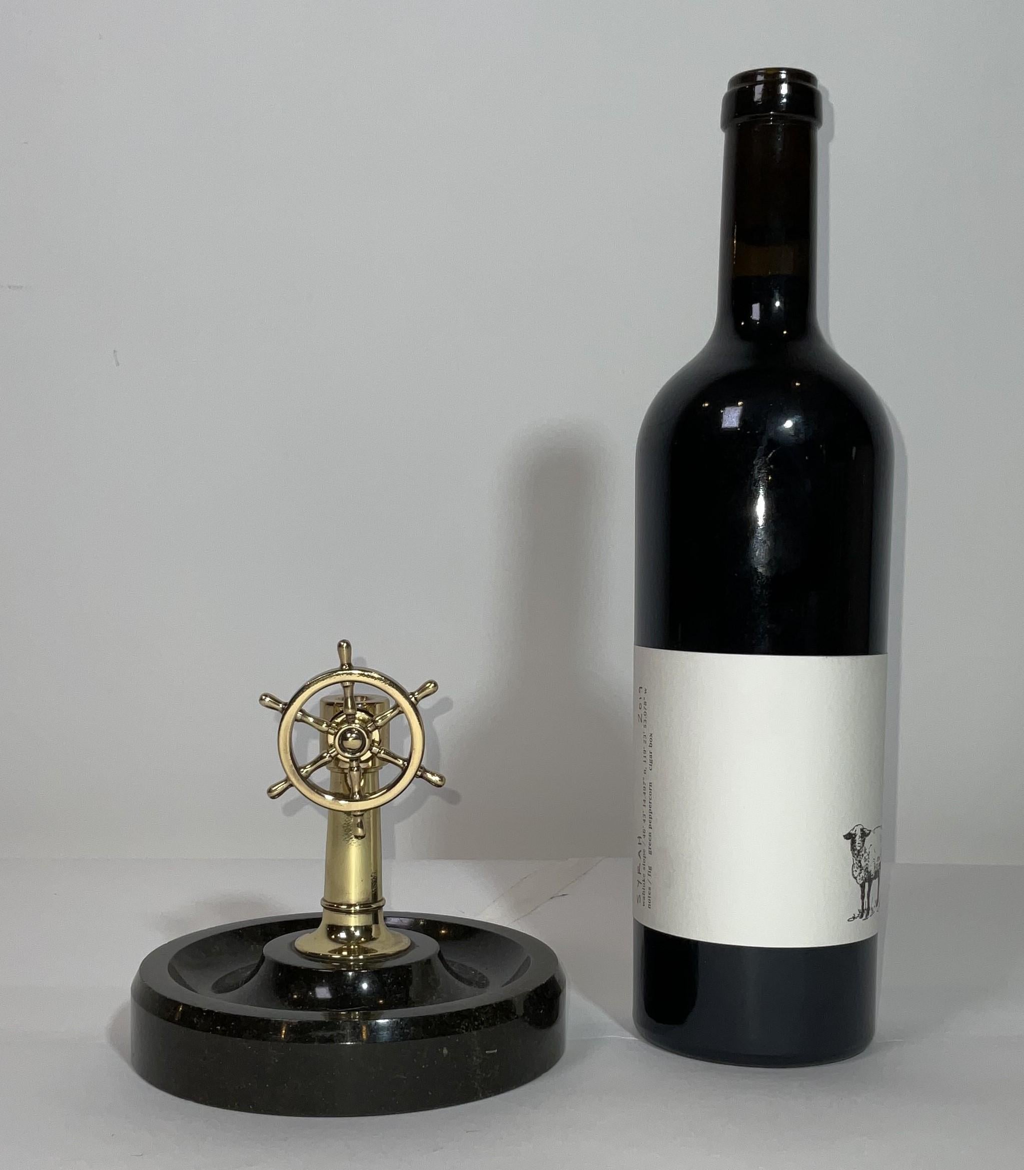Nautical cigar cutter with a hole and cutting blade in the column. When the wheel is turned, the blade is engaged to cut the tip off the cigar. This cutter has been meticulously polished and lacquered. The cutter is mounted to a marble base with an