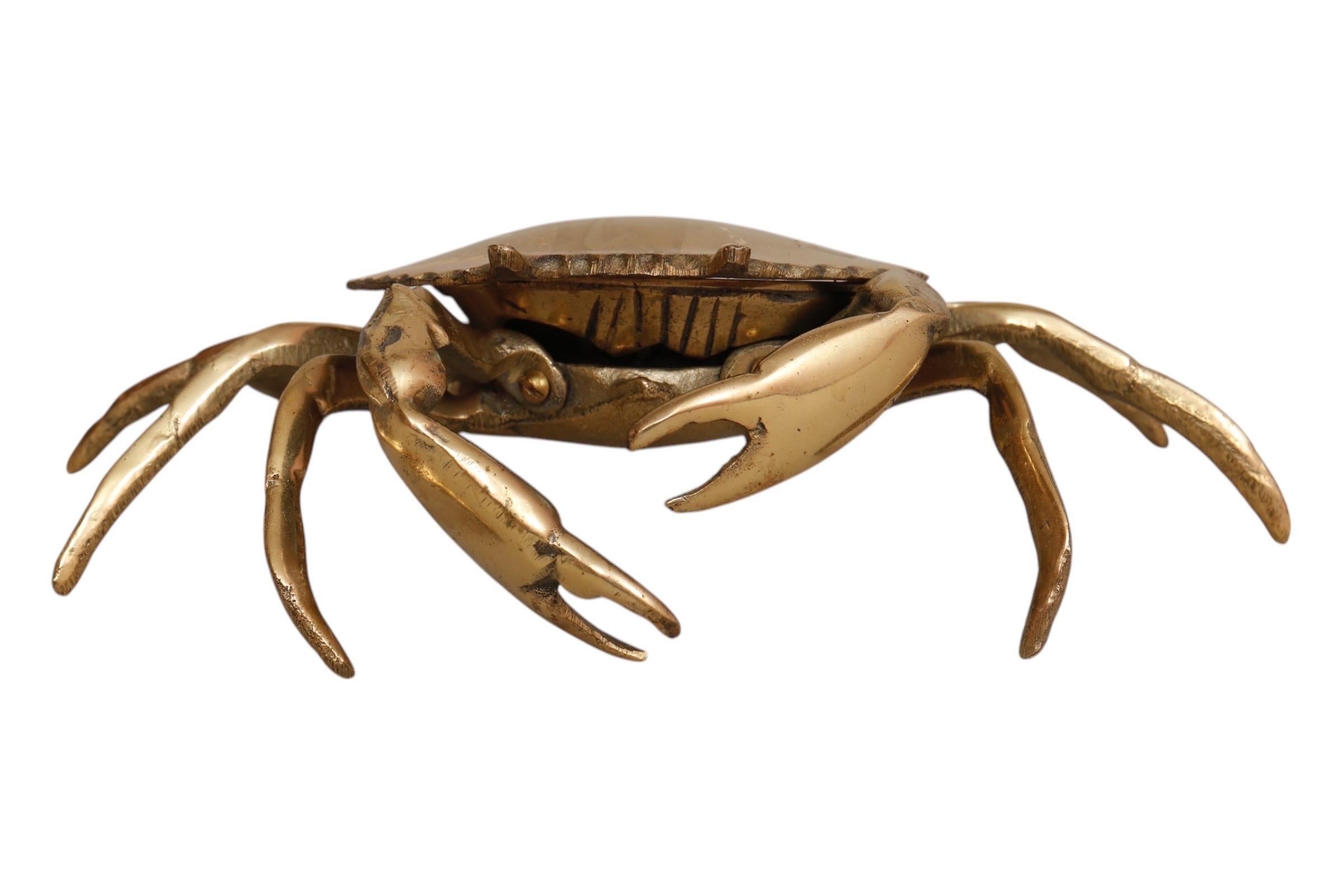 A 1960’s ashtray in the shape of a blue crab, identified by its paddle-shaped back legs. Made of solid brass, the top shell of the crab is hinged at the back and lifts to reveal a removable ashtray with two cigarette rests. Front claws are movable