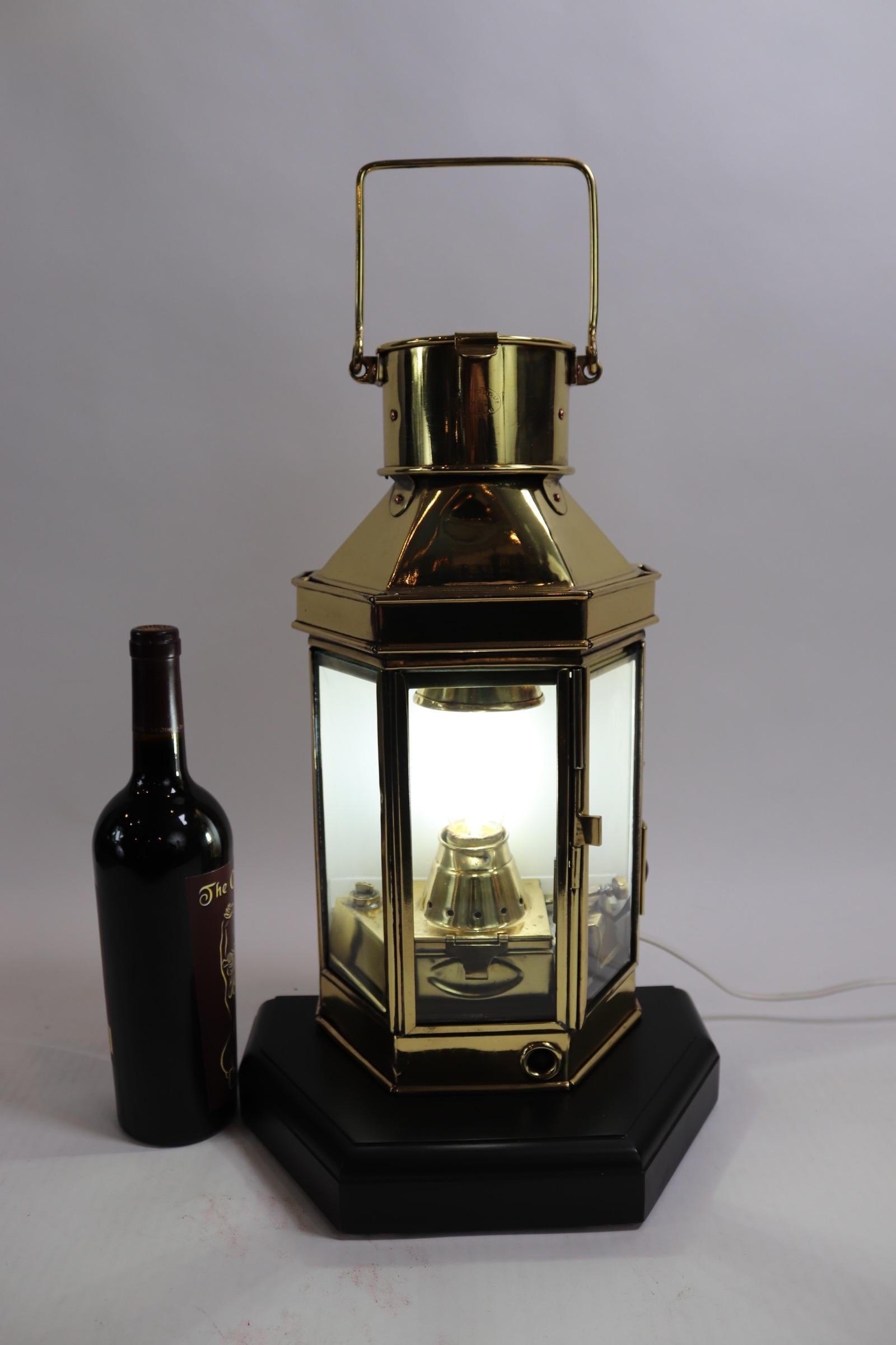 Solid brass ships cabin lantern with highly polished and lacquered finish, mounted to a thick custom wood base with rich dark finish. Chimney is engraved with makers name of BULPITT and Sons Birmingham, 1941. Weight is 14 pounds.