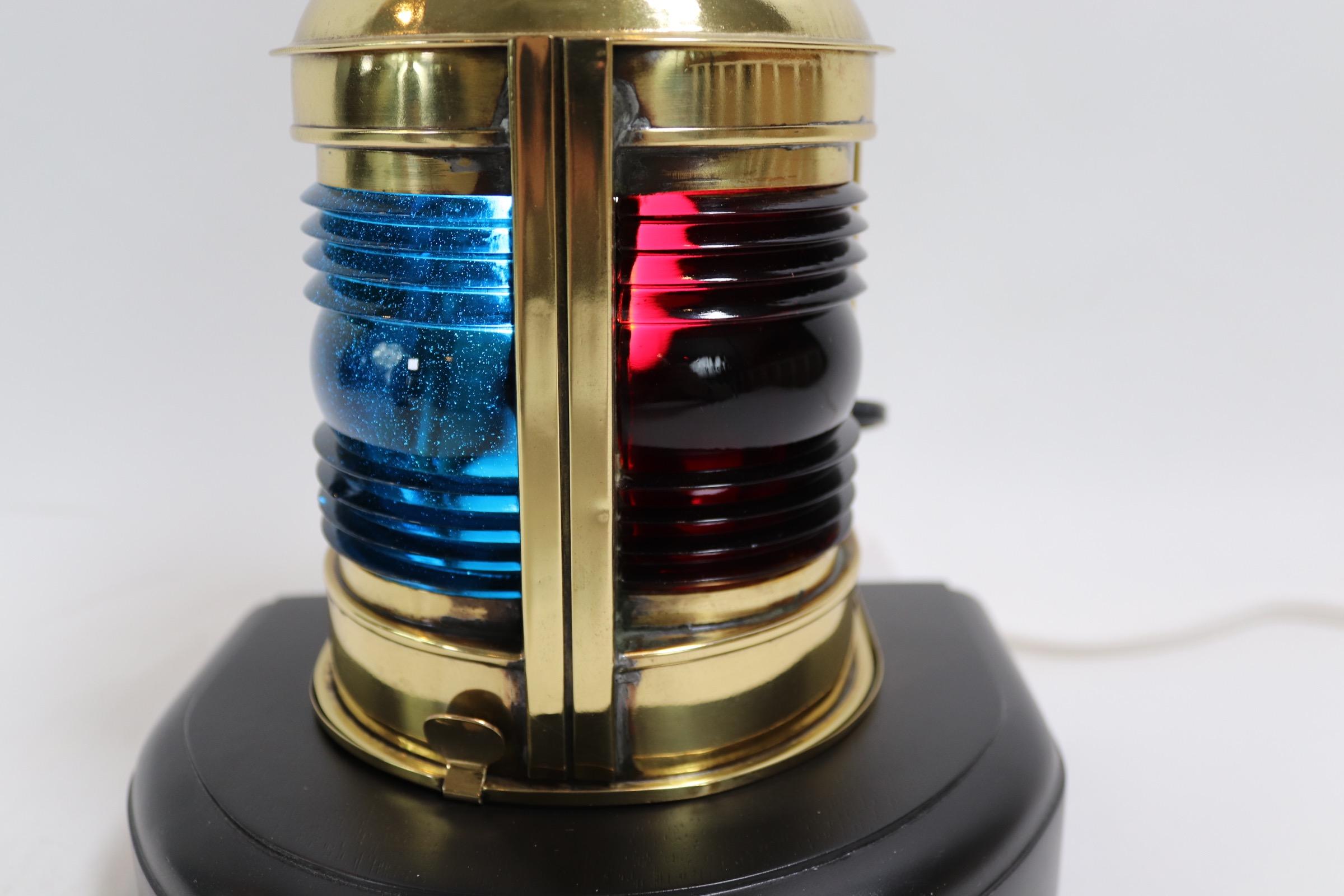 Highly polished and lacquered nautical boat lantern with red and blue Fresnel lenses. Mounted to a thick wood base with dark finish. Lantern has been wired for home use. Weight is 3 pounds.