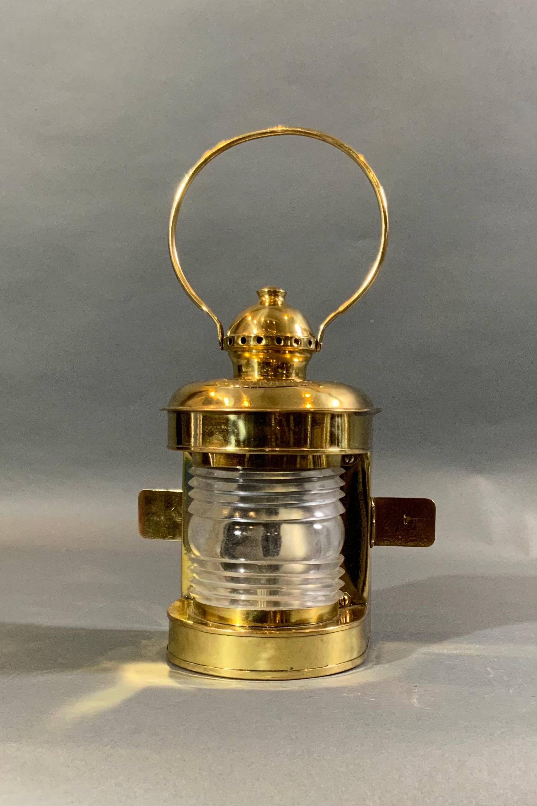 Ships lantern that has been meticulously polished and lacquered. Hinged rear door, Fresnel lens, vented top, carry handle. With polished burner inside. By Universal Metal Spinning and Stamping CO New York. Weight is 4 lbs. 10
