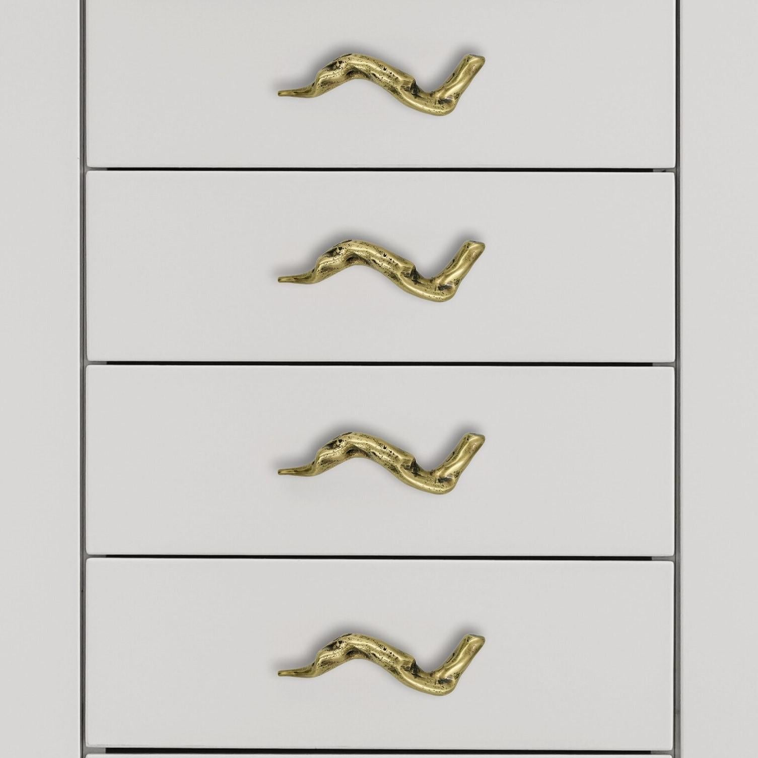 Cette poignée de meuble en laiton massif appartient à la collection Empreintes. Son contour irrégulier s'inspire de formes naturelles, comme une Branch, sans symétrie prédéfinie. La pièce présente un profil sinueux, d'une longueur de 12 cm, avec un