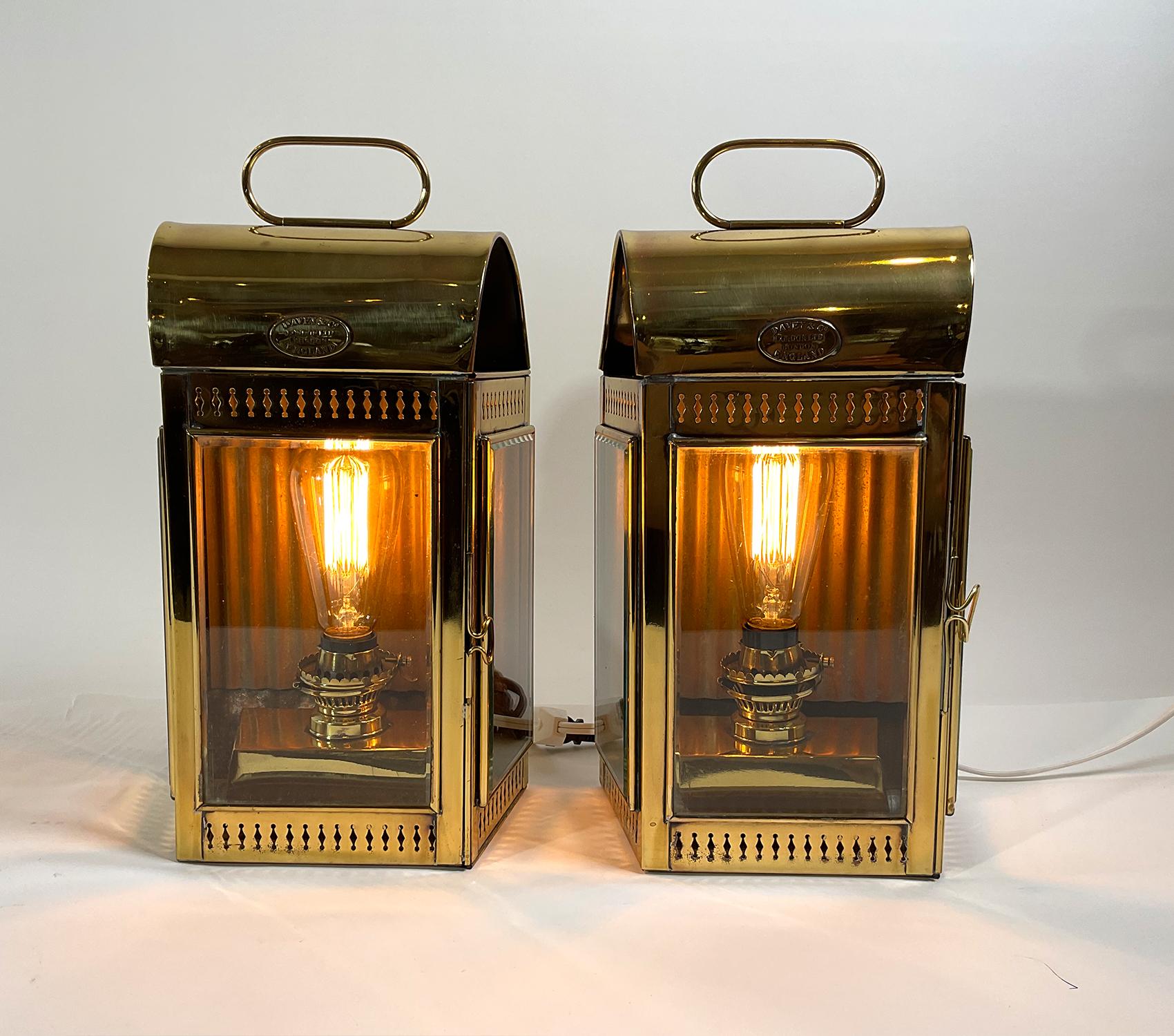 Pair of solid brass yacht cabin lanterns by the venerable English maker Davey and Company of London. With brass makers badges. Beveled glass panes, two hinged doors. The burners have been retrofitted with electric sockets for home use. Polished and