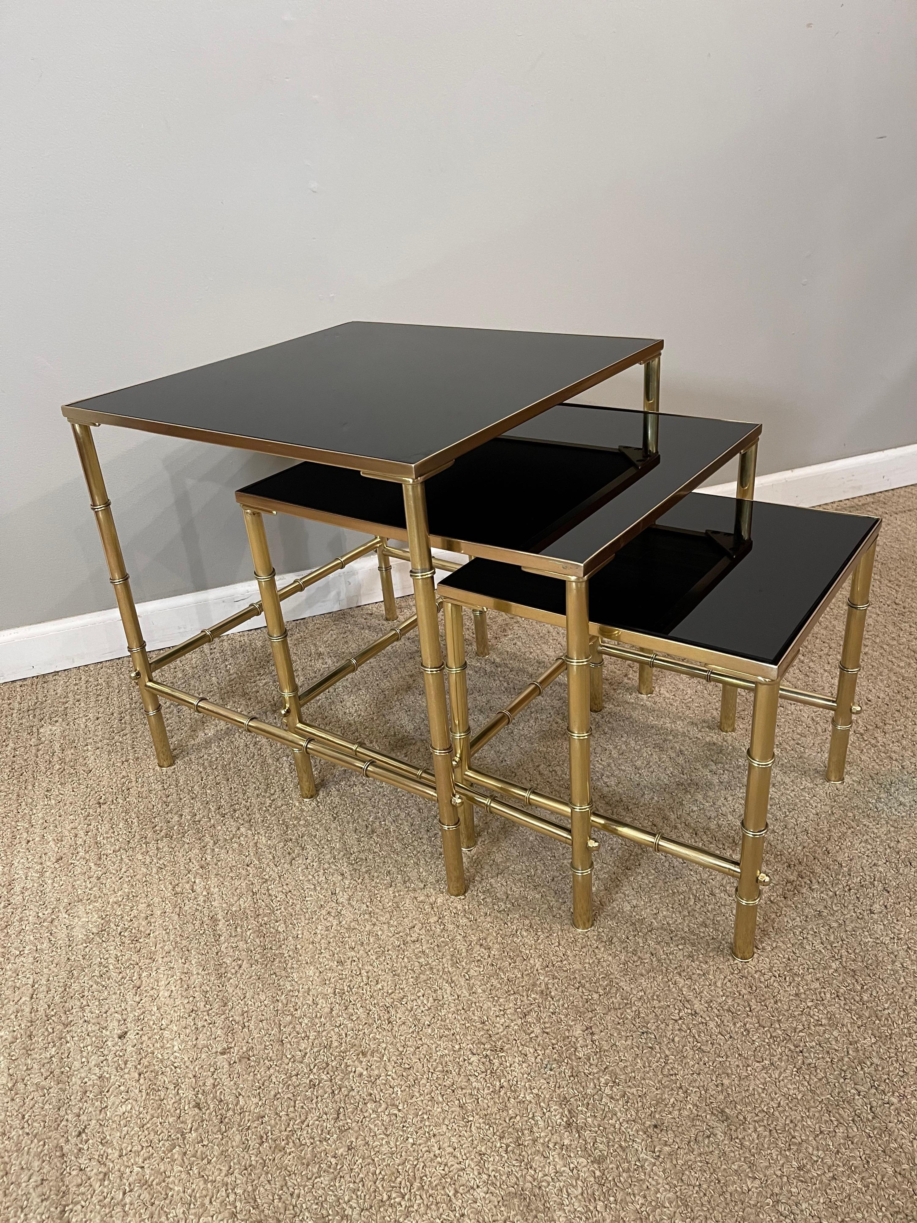 A beautiful set of Mid-Century Modern, Jansen nesting tables with 

Black glass top. Brass has been polished & sealed. Tables retain the

Original glass, glass has minor scratches consistent with age & use.