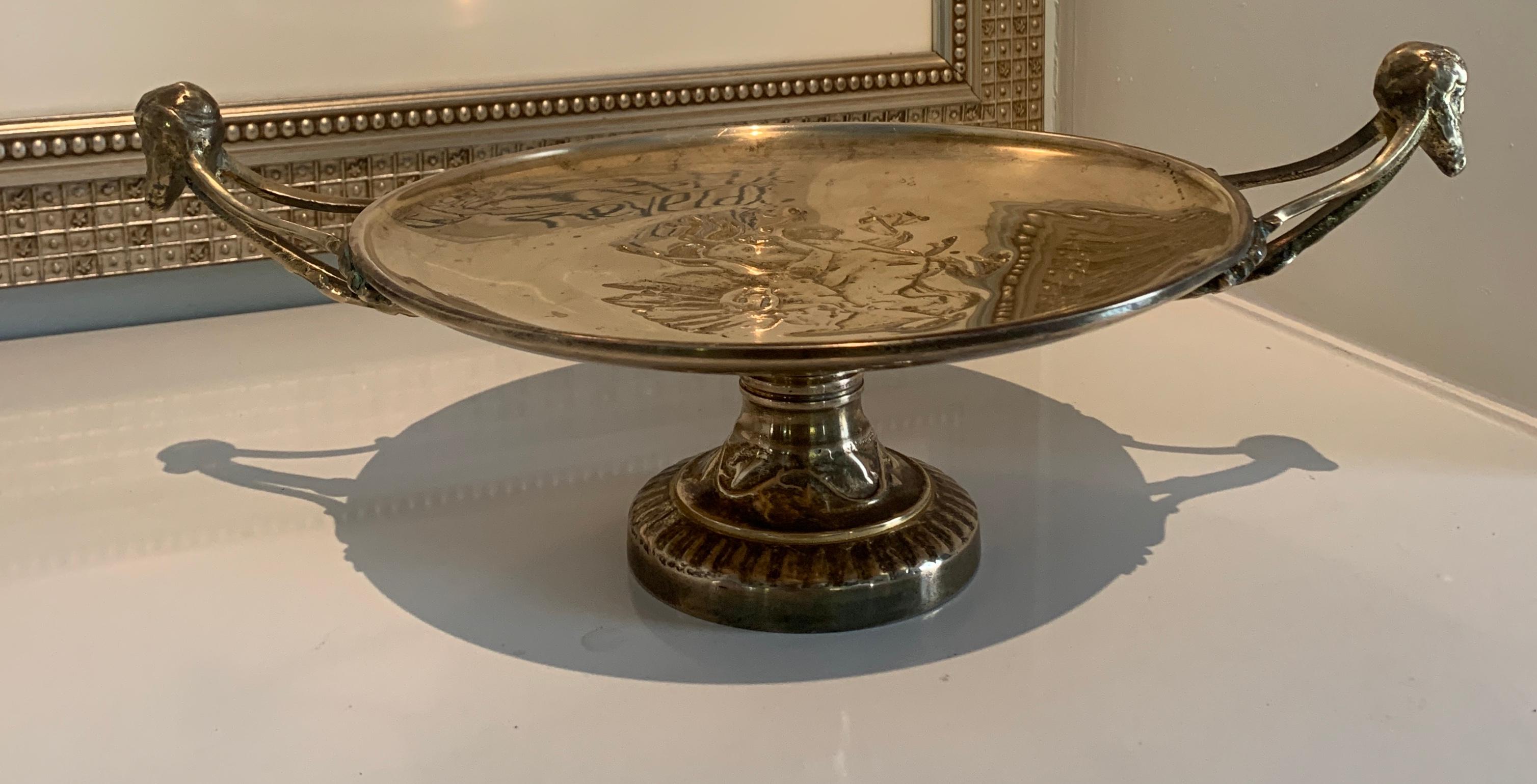 A wonderful, and very heavy, for it's size, solid brass footed Tazza by Maitland Smith. The bowl features elongated leads that end in male heads as handles with an etched brass detail in the plate above the pedestal. A stunning center piece or catch