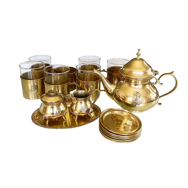 A vintage nautical motif solid brass and glass tea and coffee service for six. This set includes 6 brass mugs with 6 glass inserts, 6 brass coasters, 1 large brass tea or coffee kettle, 1 creamer, 1 sugar bowl, and 1 oval display plate for creamer