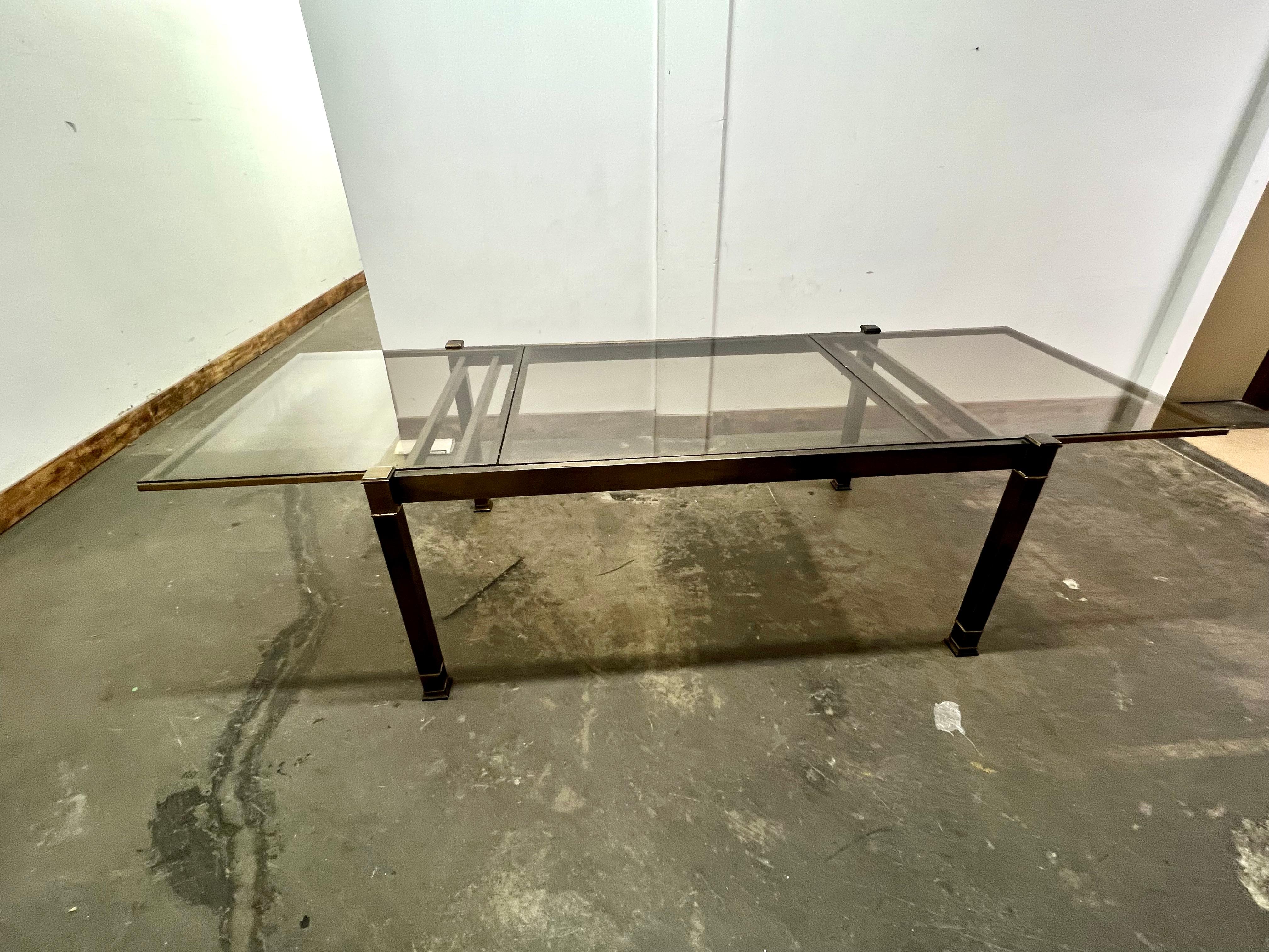 A wonderful Mid Century Modern solid brass and smoked glass Mastercraft table.   The table expands from 67