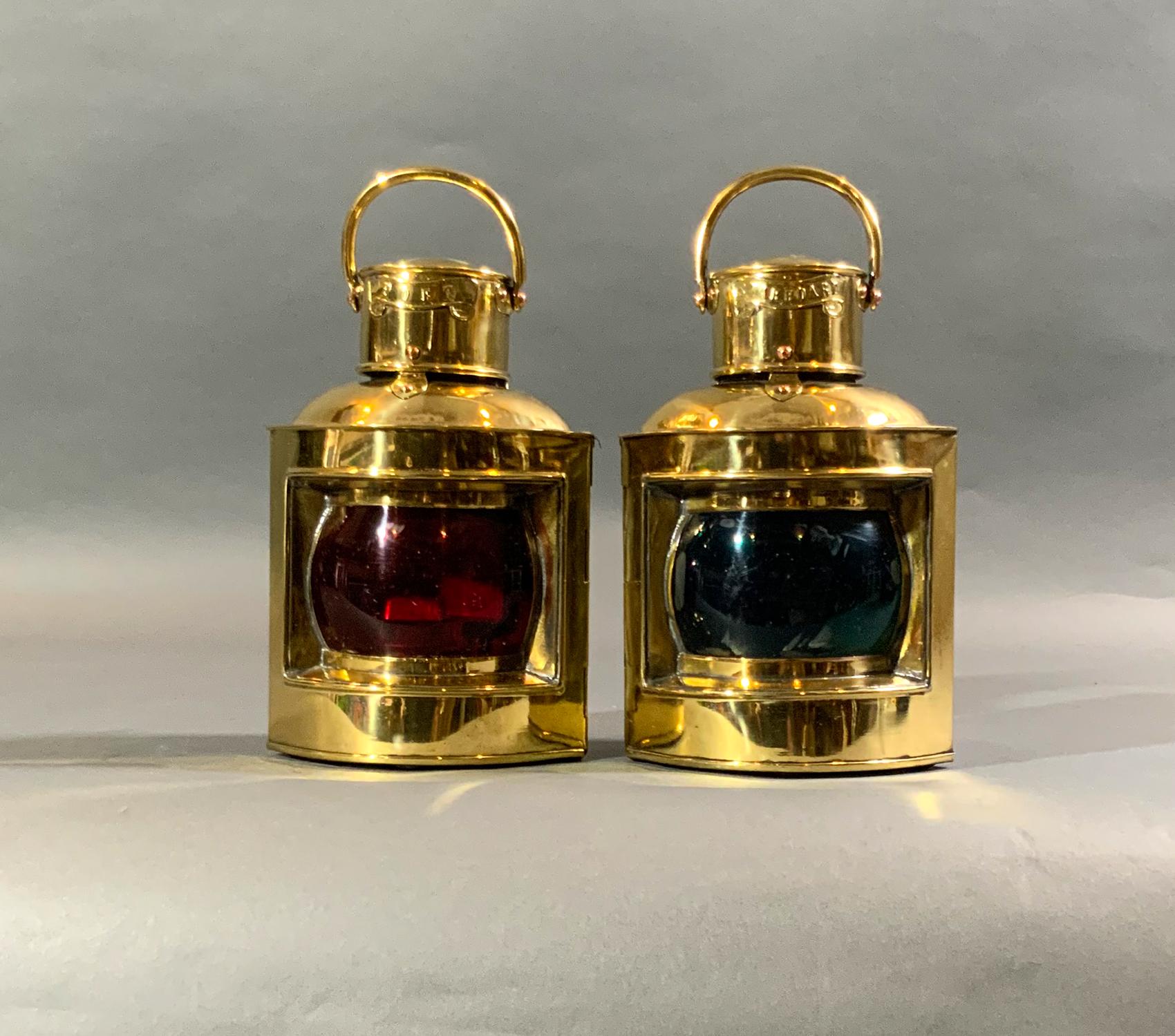 Fabulous antique pair of highly polished and lacquered ship lanterns. Gleaming finish. Red and green glass lenses. Vented tops with carry handles. Brass port and starboard badges. Choice pair of original nautical lanterns. With makers plates from