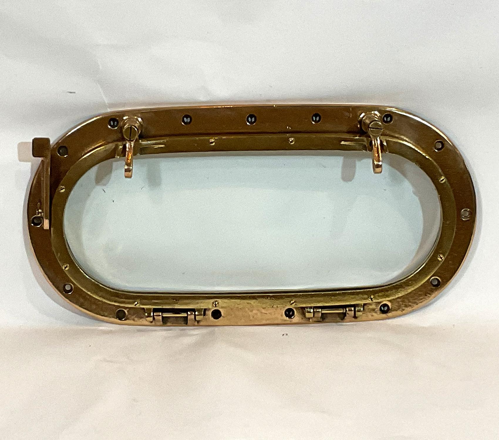 Highly polished boat porthole with hinged door with two latches. Great nautical relic. Clear glass.

Weight: 14 LBS
Overall Dimensions: 2” H x 21” L x 11” W
Glass 17 1/2