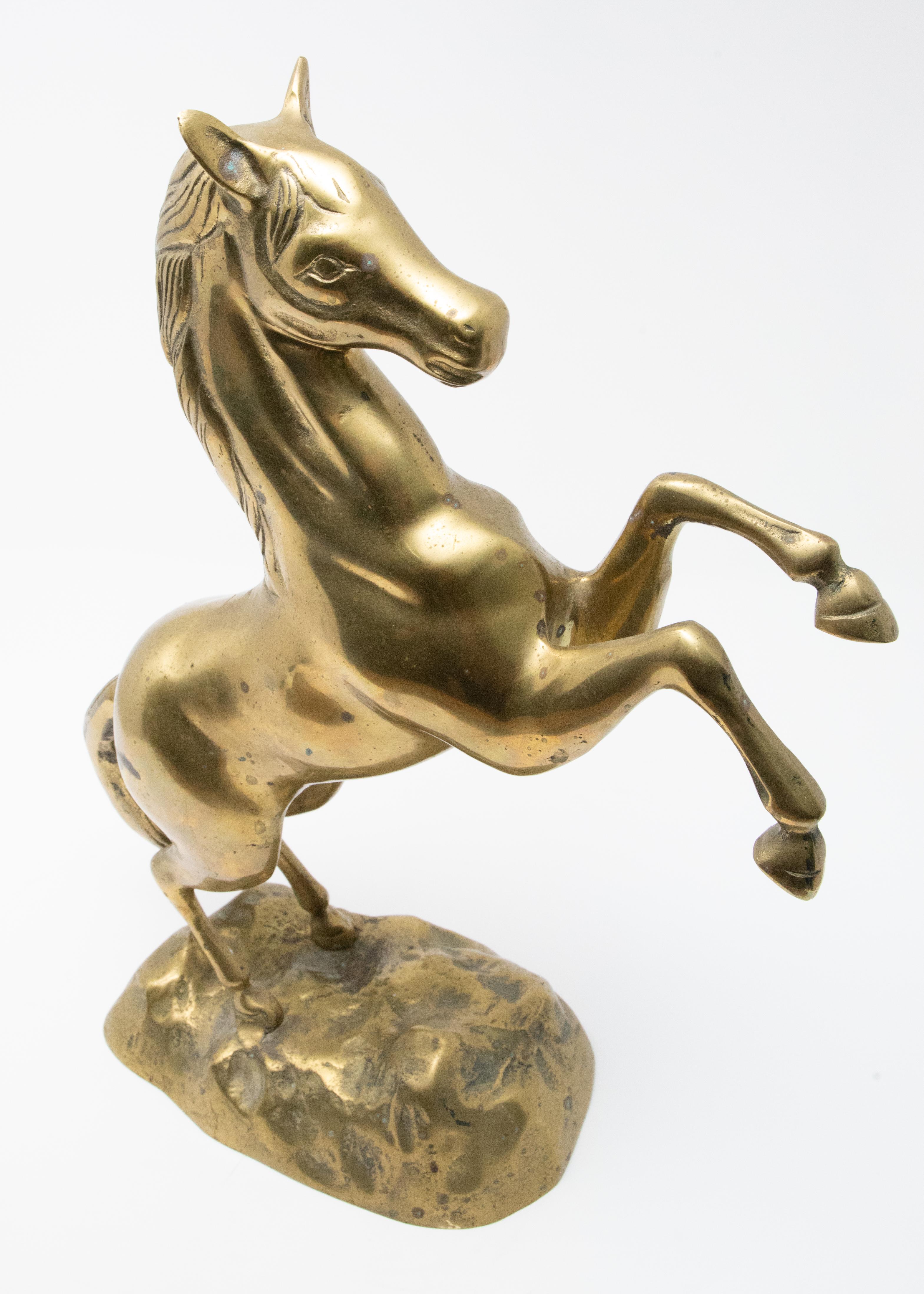 Beautiful sculpture of a raring horse out of brass. Starting on the base the two hind legs standing on the ground with engraving in the brass to look like grass. The tail is long and swooshes downward. Up the back of the horse to the mane and the