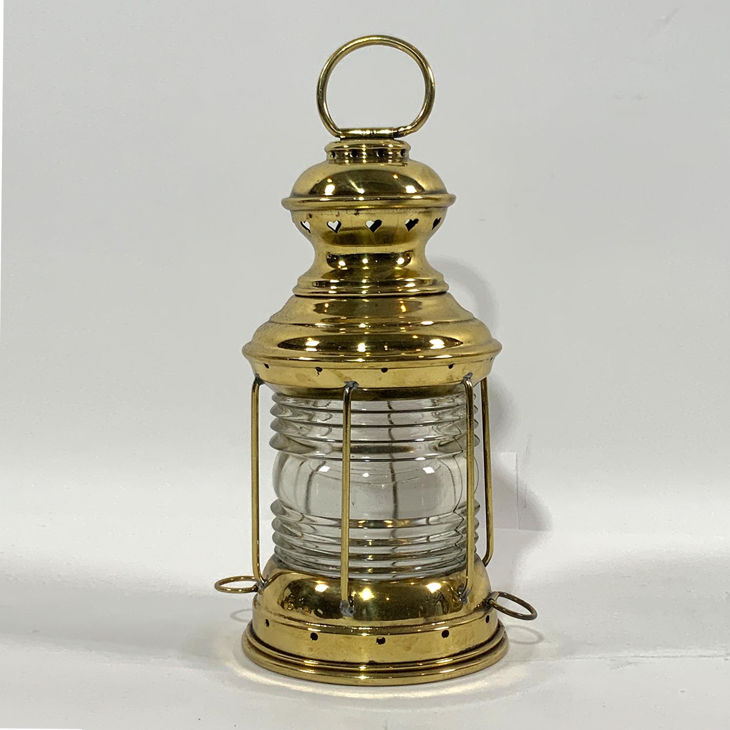 Brass boat lantern by Perko of Brooklyn, New York. Fresnel glass lens. With protective brass bars and hoisting ring. Meticulously polished and lacquered. Circa 1940. With original oil burner.