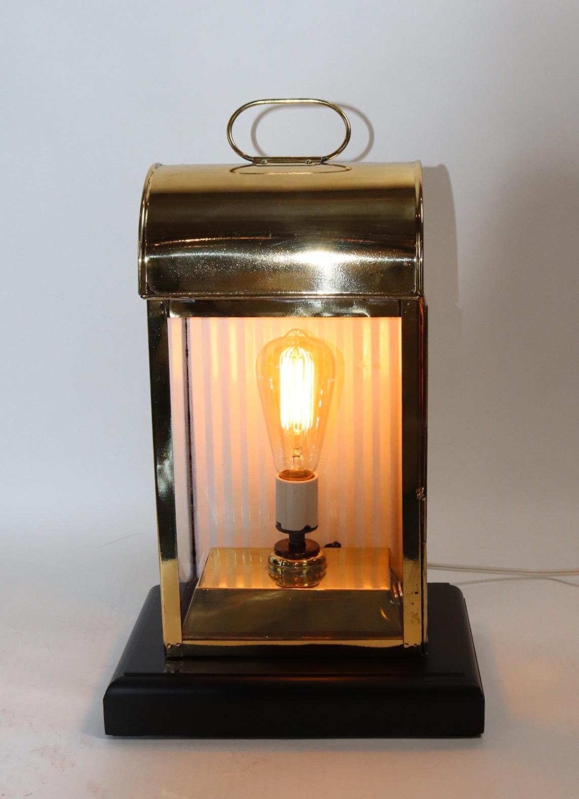 Solid brass ships cabin lantern with three glass panes, hinged access door, carry handle, mounted to a custom wood base with rich dark finish. Wired for home display. Weight is 8 pounds.