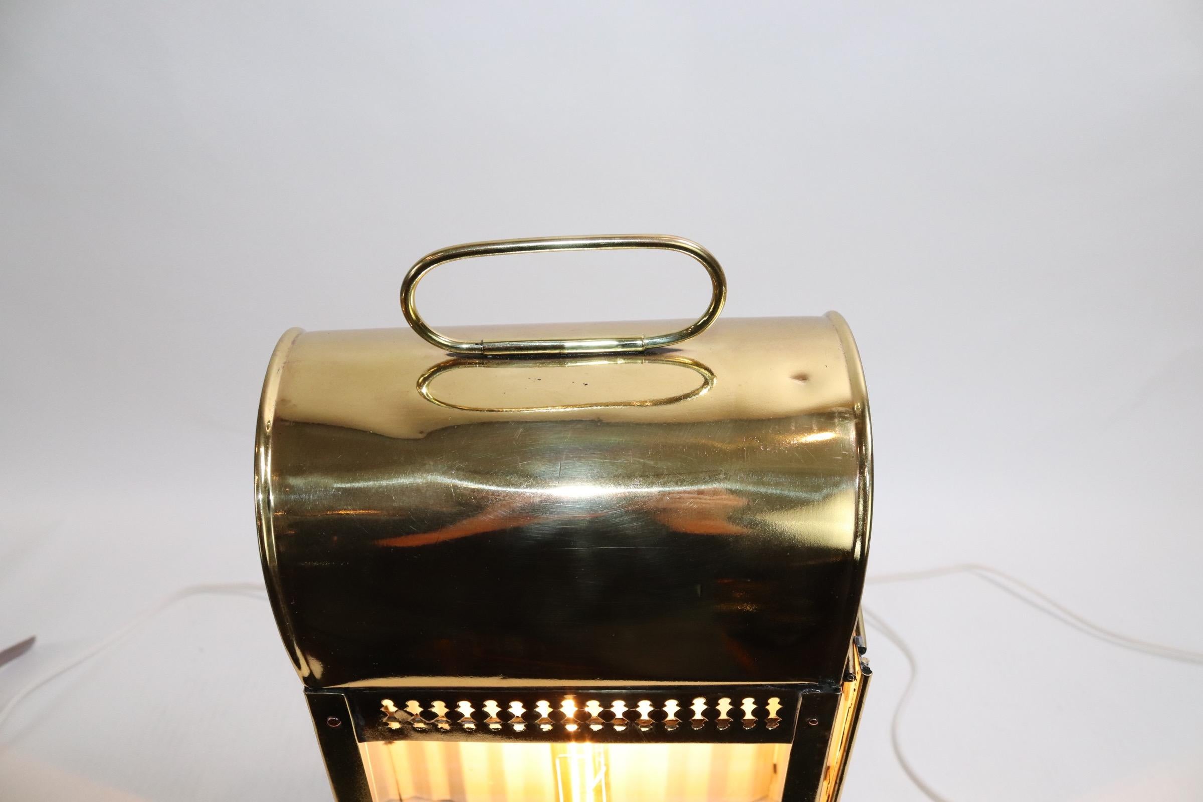 Solid brass cabin lantern from a yacht. Highly polished and lacquered and mounted to a custom wood base. Lantern has a curved vented top with carry handle, mounting flanges on the back. The lantern has been electrified and fitted with a vintage