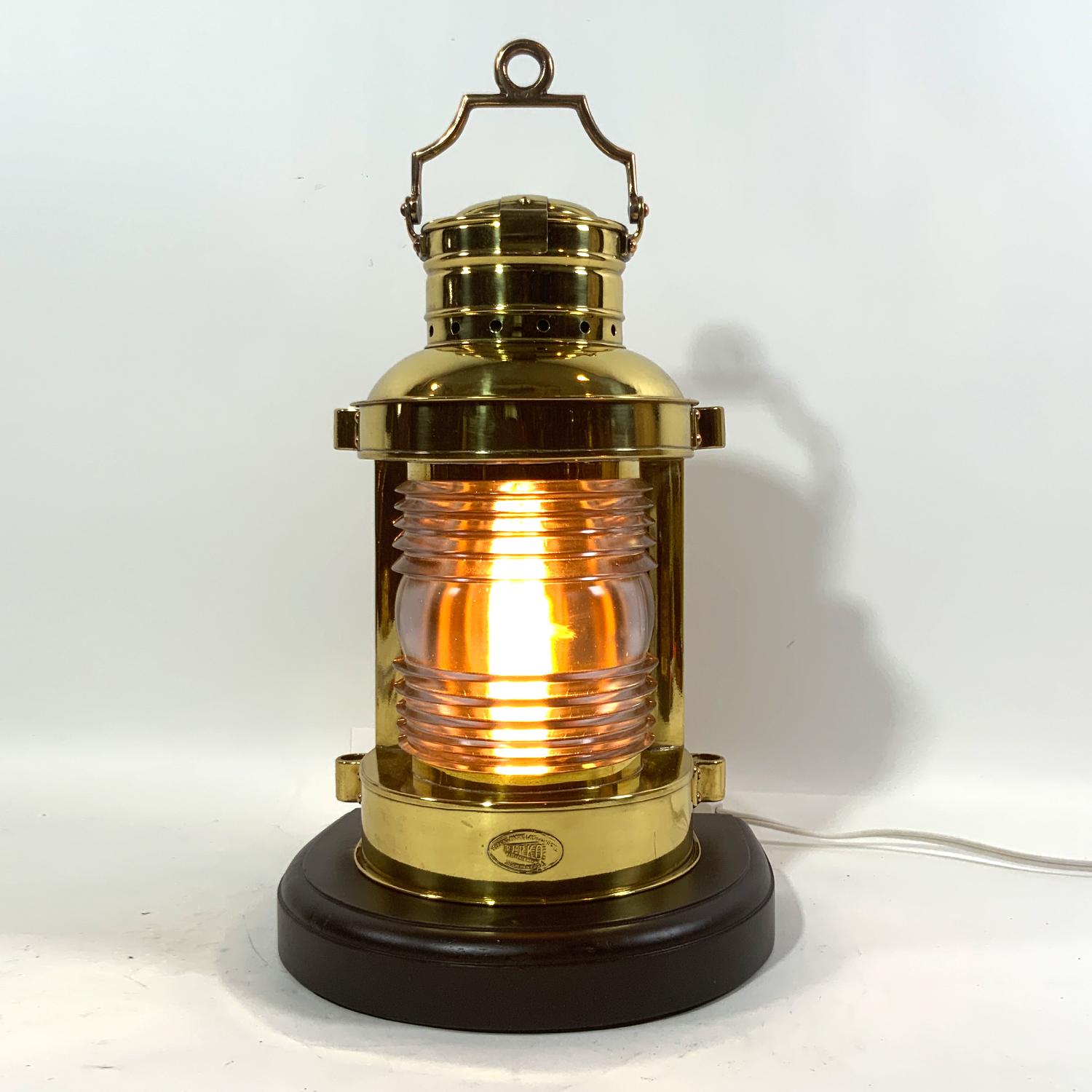 Highly polished and lacquered ship's masthead lantern by Perko. Fitted with a Fresnel lens. Mounted to a mahogany base with routed edge. Rewired for home use. Heavy carry handle. Exceptional condition. Circa 1950. Superb display.