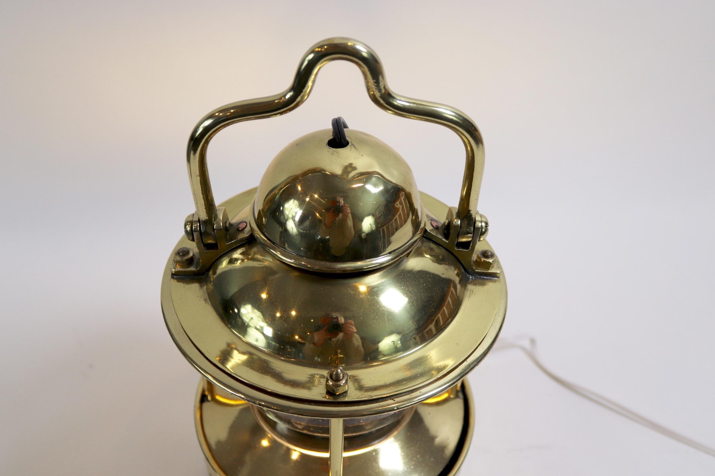 Highly polished mast mounted ships navigational signal lamp that would be used to send signals by raising and lowering the brass shroud. The heavy glass lens is missing a piece near the top so please look at photos. There is a hoisting ring and