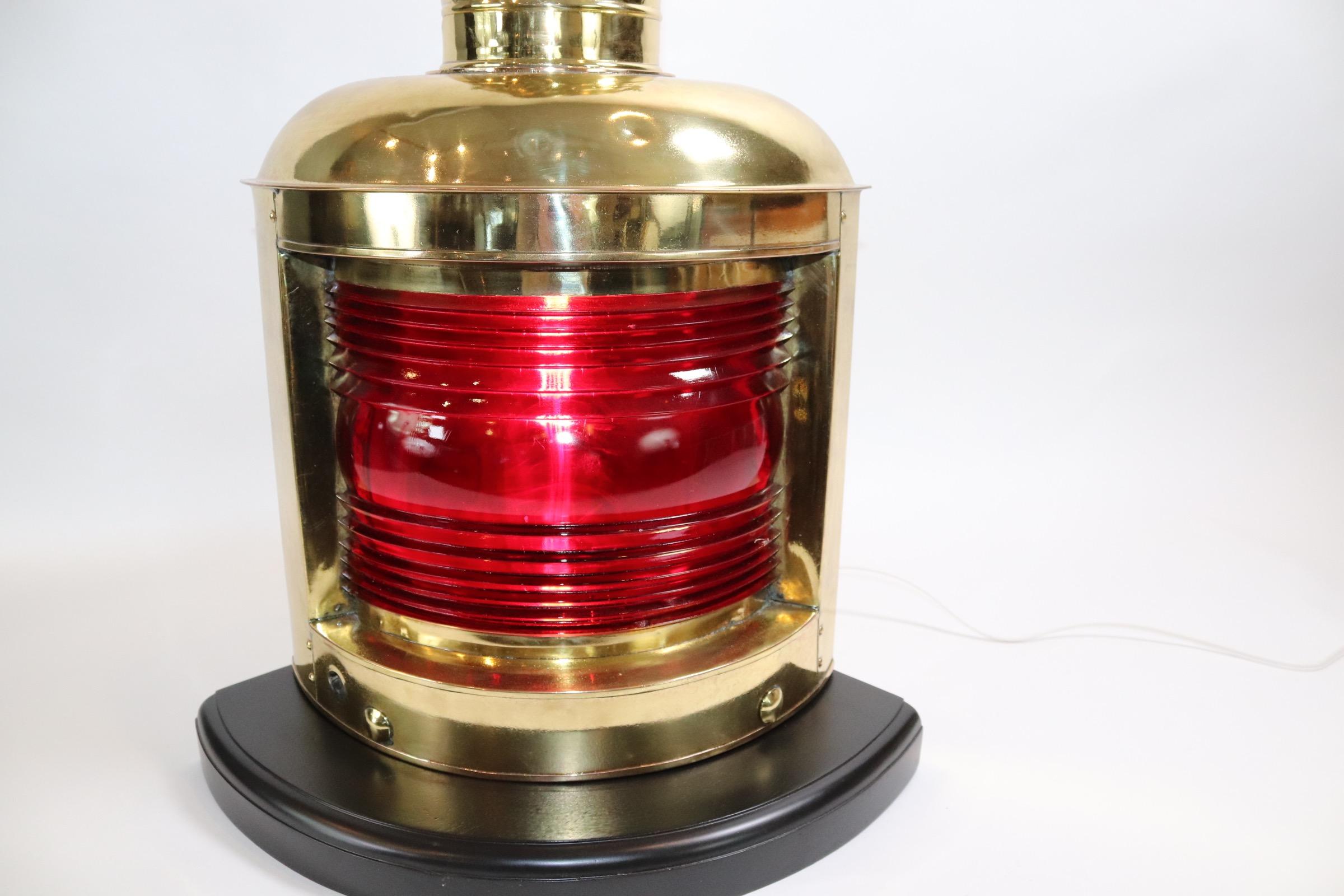 Brass ships port lantern with highly polished and lacquered finish. Lantern has been mounted to a thick wood base with rich dark finish and has been wired for home use. Beautiful dark rich lens. Weight is 20 pounds.