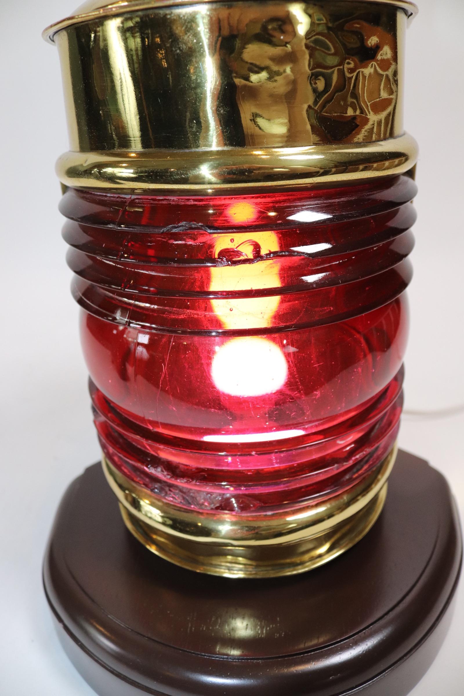 Highly polished and lacquered ships port lantern with Fresnel glass lens, vented top and mounting tabs. Very unusual shape. Mounted to a custom wood base and unit has been electrified for home use. Some chips to lens. Weight is 8 pounds.