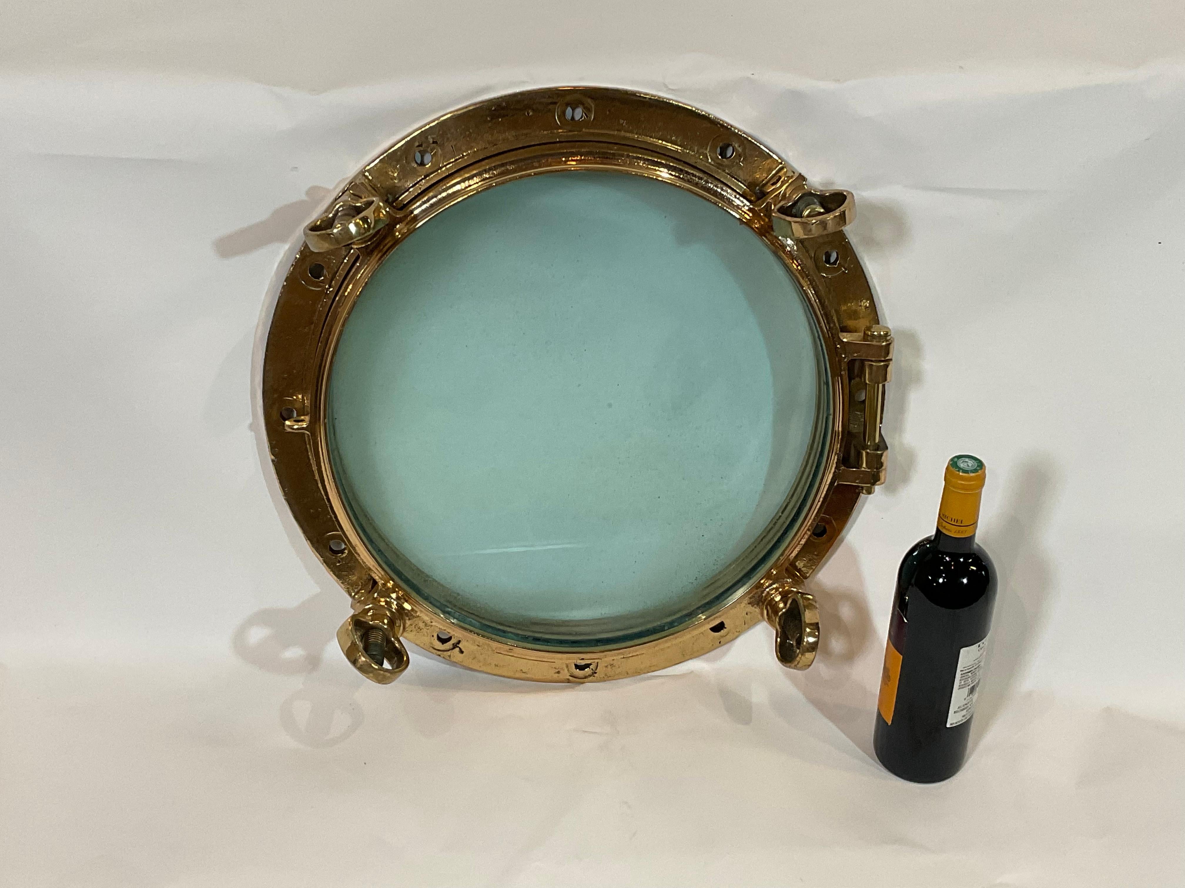 Early 20th century solid brass ships porthole. Hinged door with four dog bolts. Clear glass. Highly polished and lacquered.

Weight: 47 LBS
Overall Dimensions: 6” H x 20” Diam
Glass 16