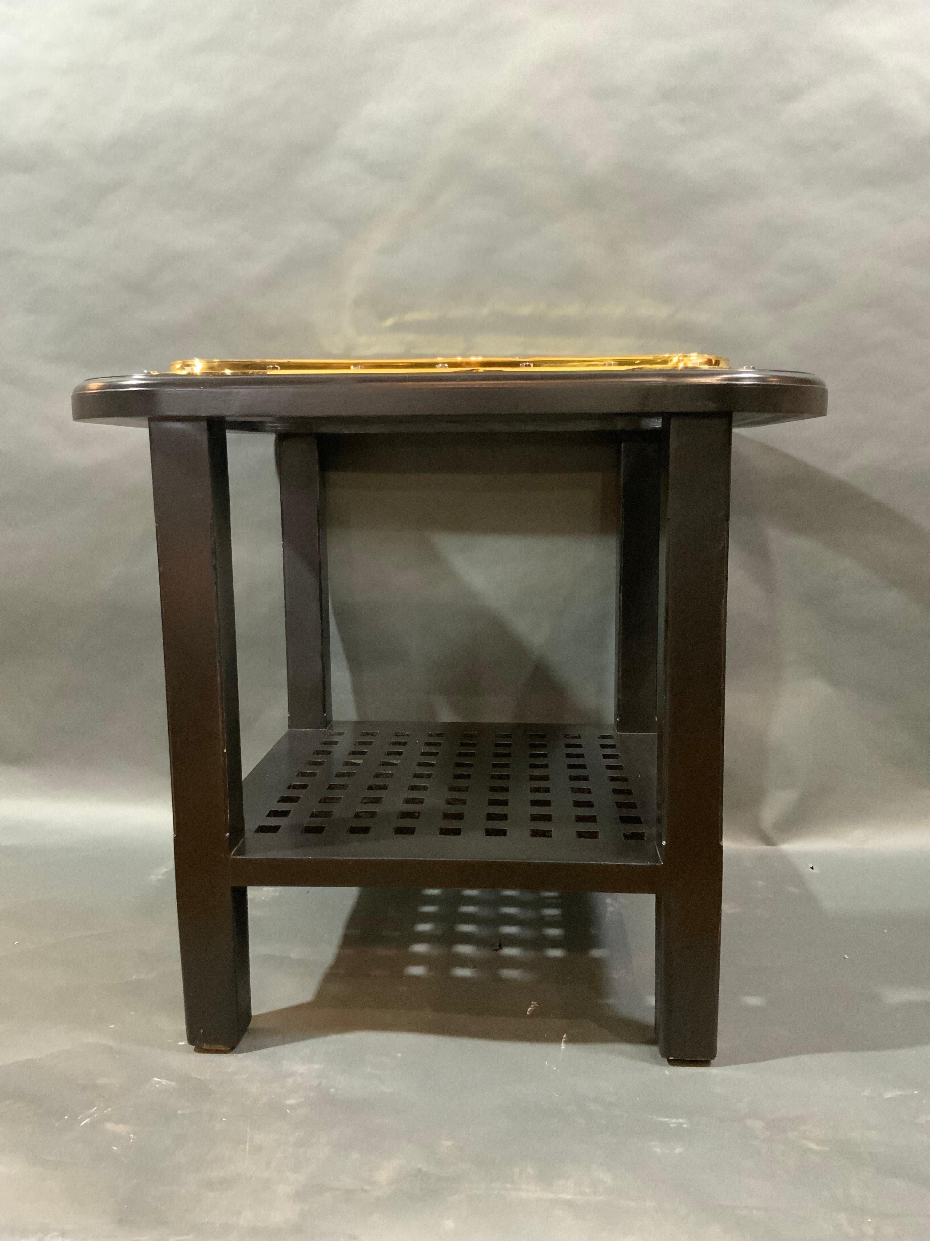Authentic solid brass ships porthole that has been meticulously polished and lacquered, then fitted to a bistro height table. Table has four tapered legs and lower shelf in the form of a ship's grating. Maritime furniture at its best. Weight is 71