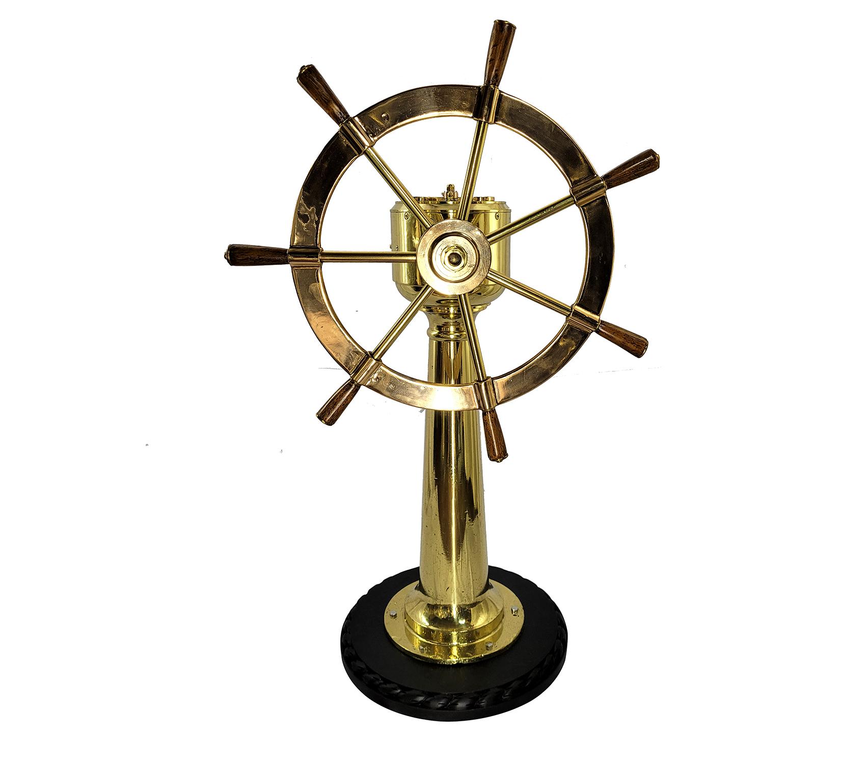 Meticulously polished and lacquered maritime relic. The very sturdy six spoke wheel has varnished wood handles, and is mounted to the geared column. The pedestal is mounted to a wood base with rope style carving. The head of the pedestal has a