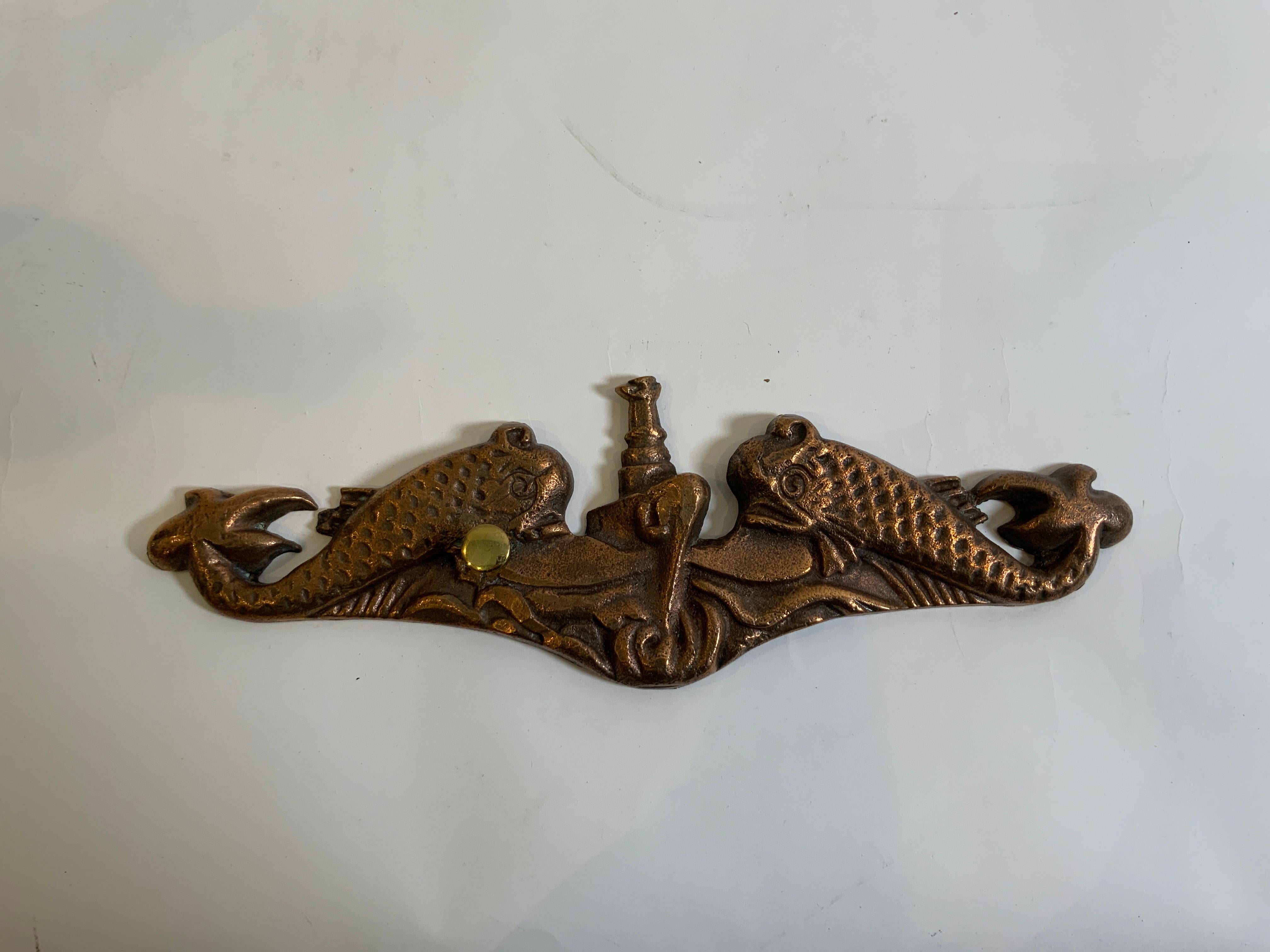 Brass submarine plaque showing a submarine passing between two mythical dolphins. Circa 1950.

Overall Dimensions: 1