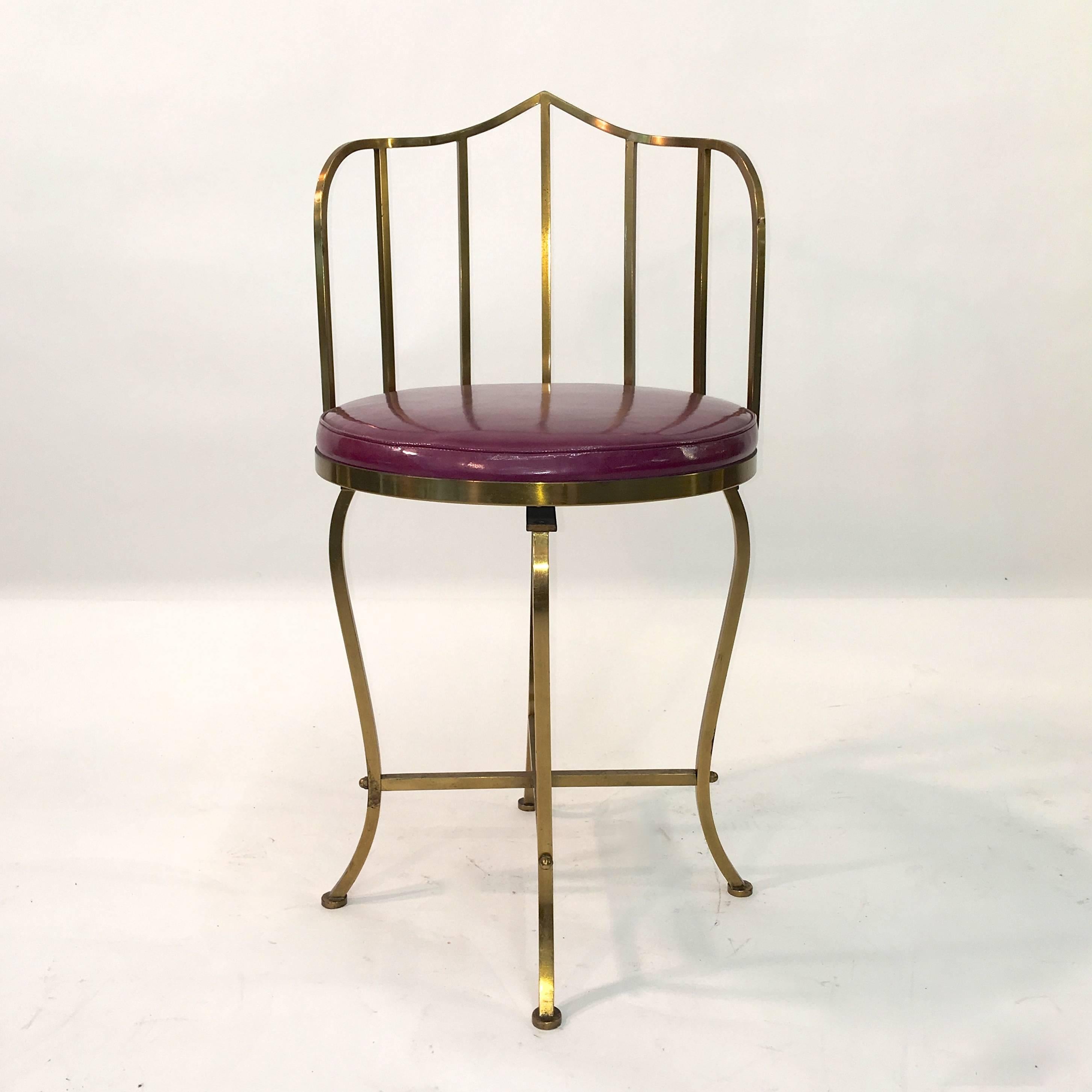 Handcrafted solid brass Hollywood Regency swivel vanity chair with round seat cushion in magenta patent leather.

The entire chair is solid brass except for the swivel mechanism itself.

Each of the legs, backrest spindles and the Ottoman-esque