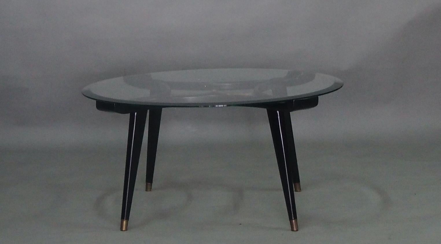 Round coffee table, designed by William Watting, produced by Fristho, the Netherlands, 1950s. A very elegant design due to the organic warm walnut wood combined with a transparent glass top. The center shows a beautiful solid brass detail, tapered